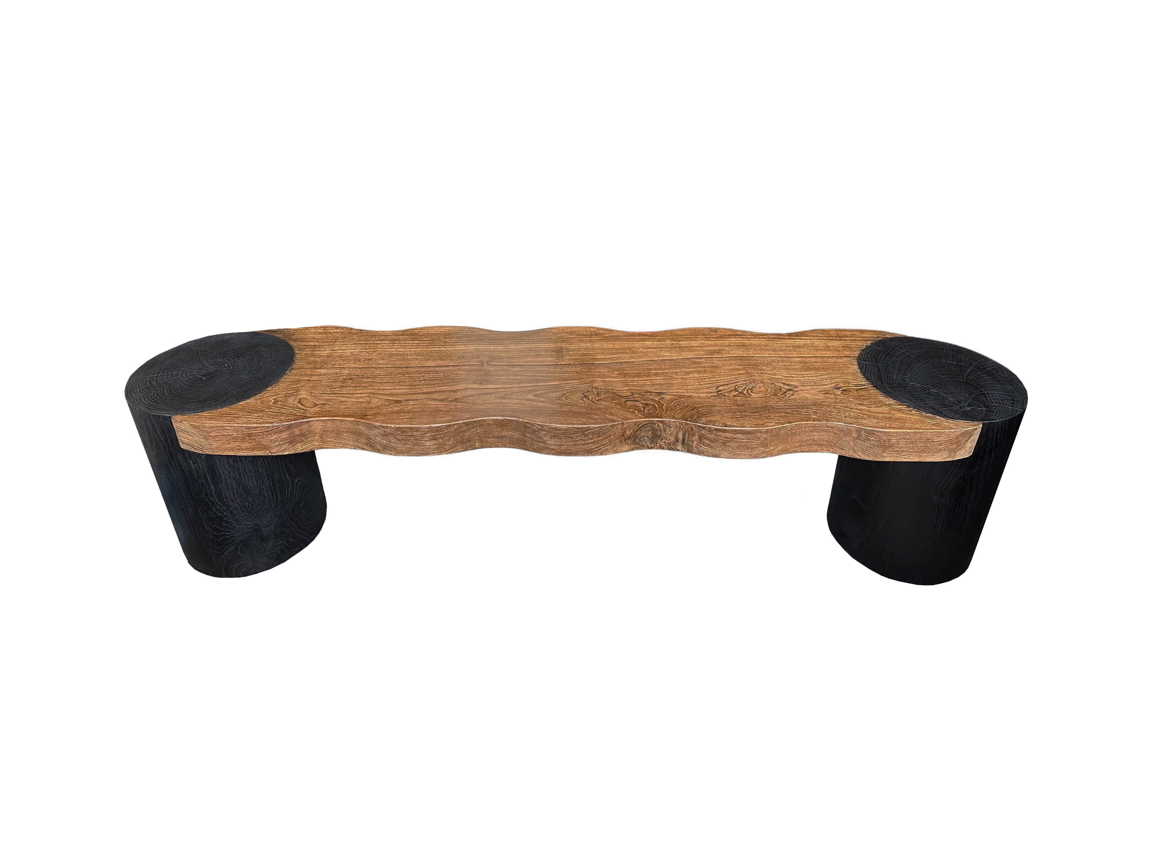 This bench was sculpted from solid teak wood with an elegant mix of contours. The wood used to create this bench is reclaimed, sourced from old pillars of traditional Java Houses, from the island of Java, Indonesia. It features a mix of wood