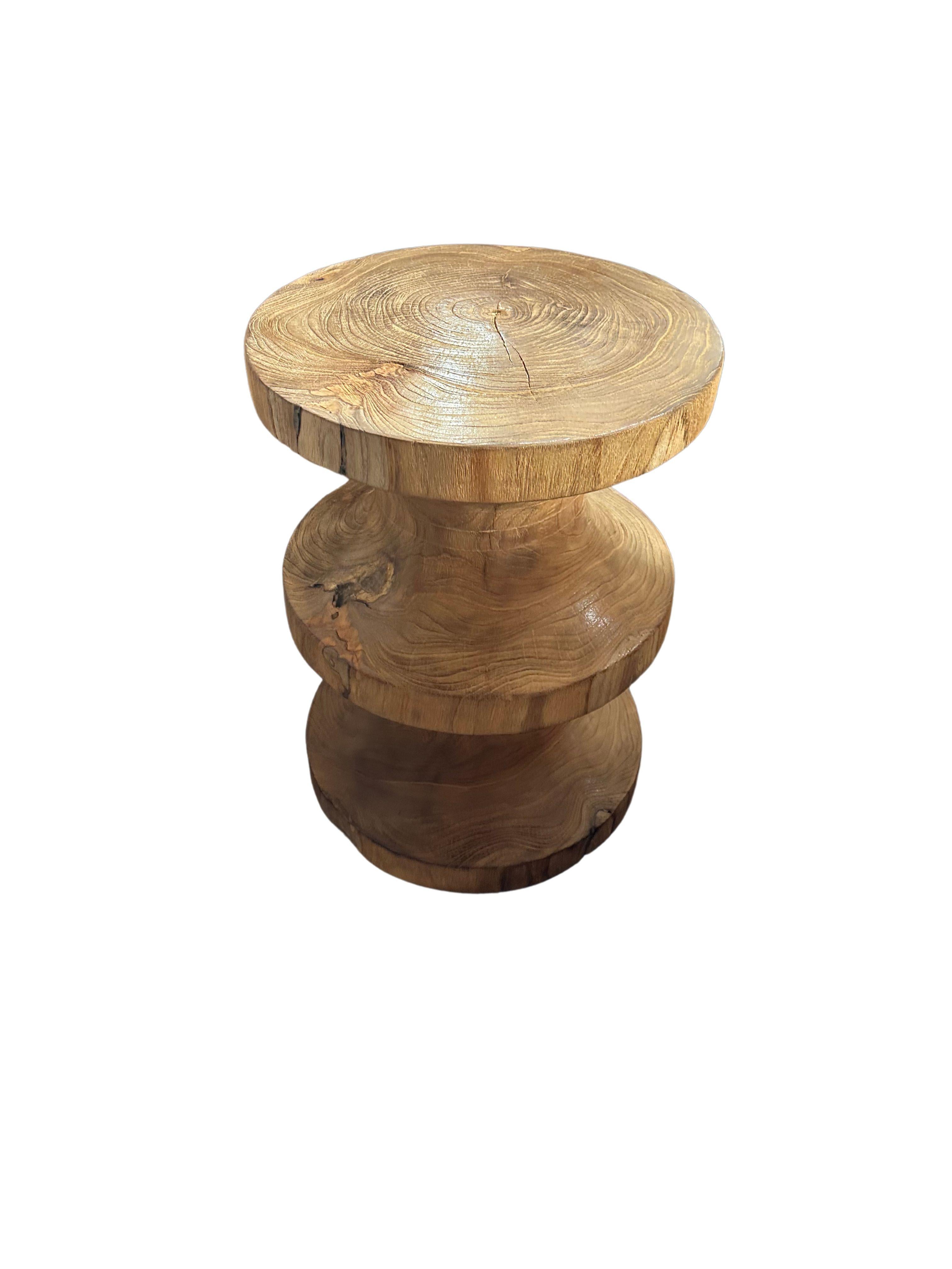 Esta escultural mesa auxiliar de madera de teca es una fusión magistral de arte y funcionalidad, que muestra la belleza natural de la madera en su forma más orgánica. Fabricada en madera de teca de primera calidad, la mesa presenta unas texturas de