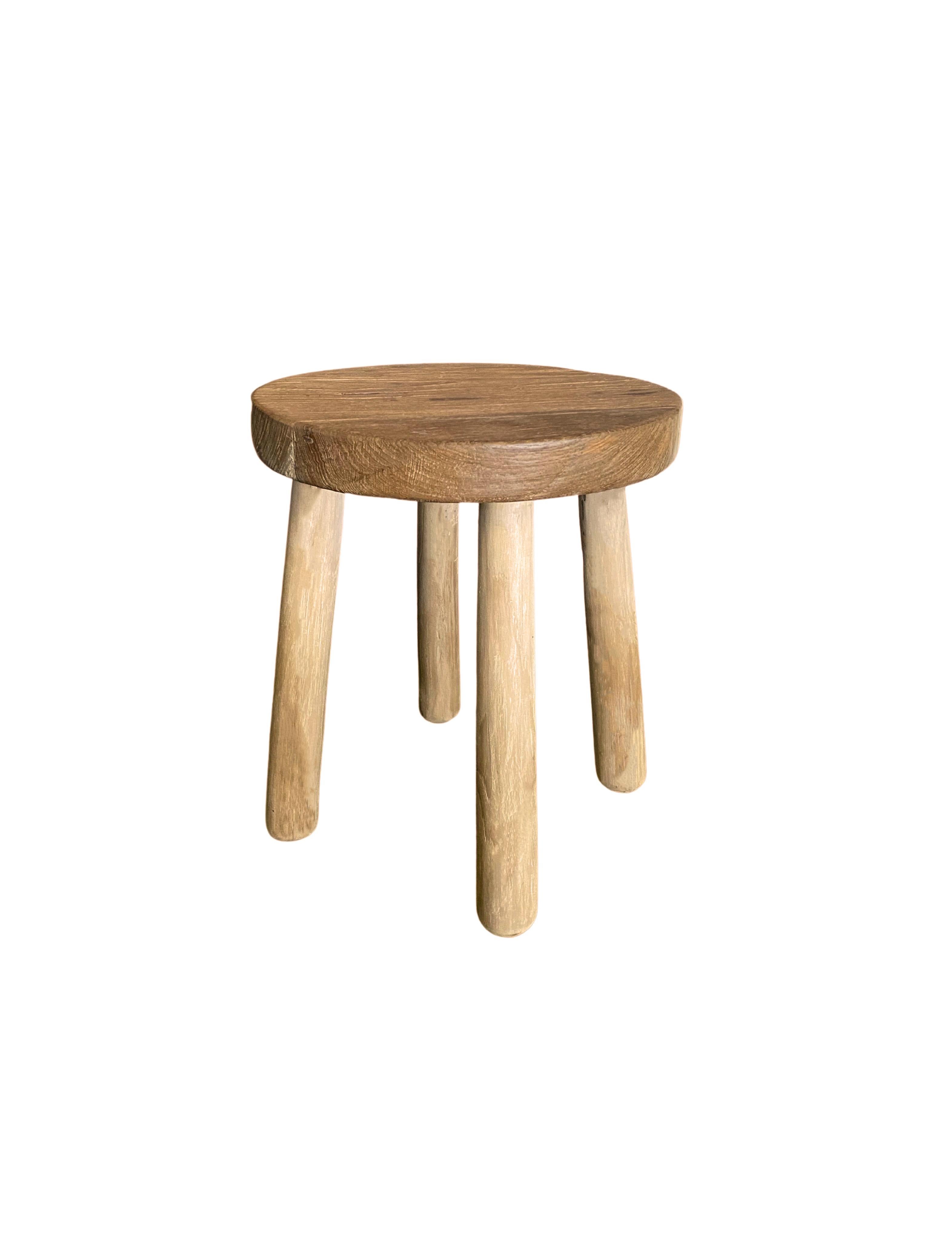 A sculptural teak wood stool with a mix of textures and shades. This stool features wonderful elongated legs that are slightly curved. The legs have been sanded down meticulously to create a smooth texture and contrast in colour to the seat which