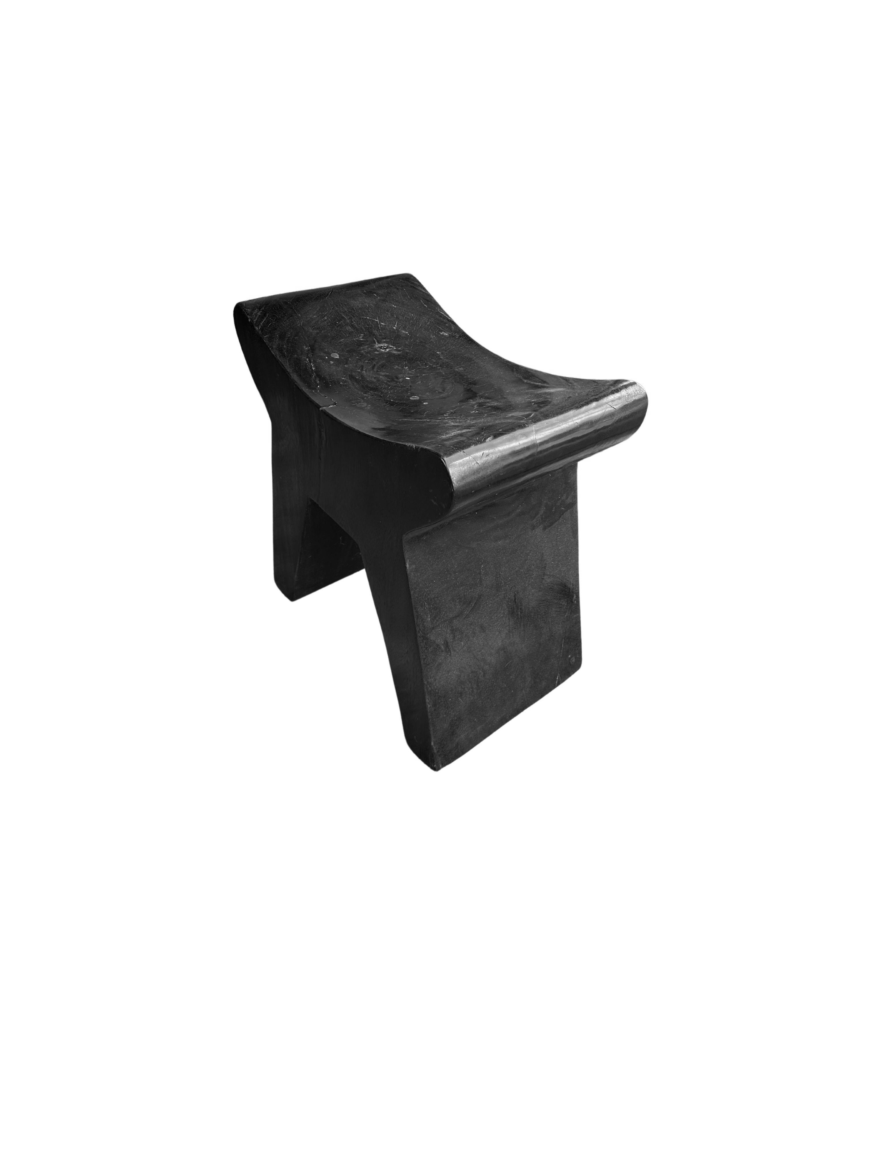 Handcrafted from a solid block of mango wood this stool features a wonderful mix of curved and straight lines. To achieve its black pigment the wood was burnt several times and finished with a clear coat. 