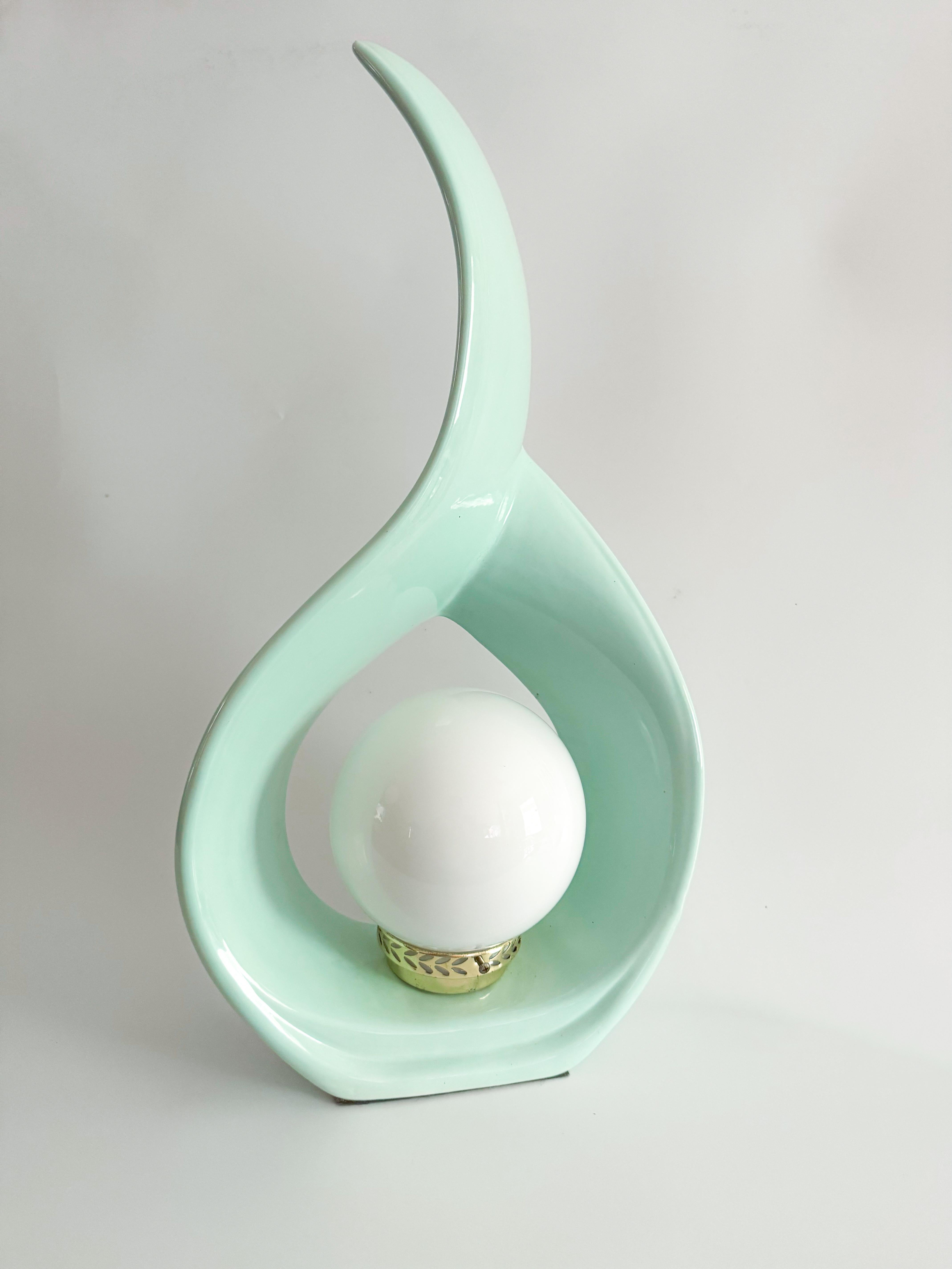Cette lampe de table sculpturale en céramique des années 1980 est une trouvaille rare et radieuse. Elle présente un émail vert menthe d'origine, une teinte peu commune, douce, brillante et pleine de charme. Sa silhouette en forme de ruban s'enroule