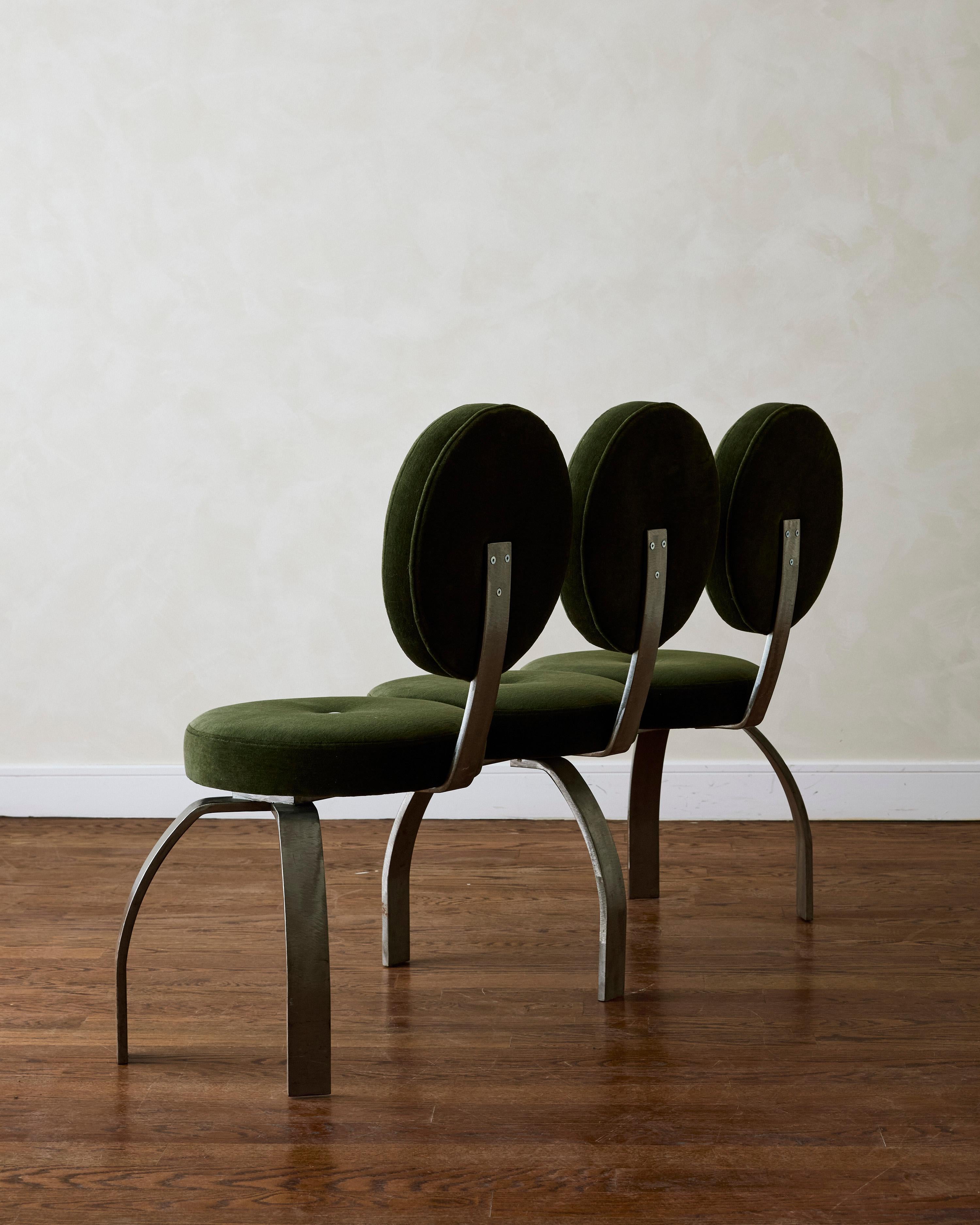 A sculptural three-seat bench, newly reupholstered in hunter green mohair, featuring white cotton buttons on the seat and backrest, and stabilized by six spider-shaped legs.


