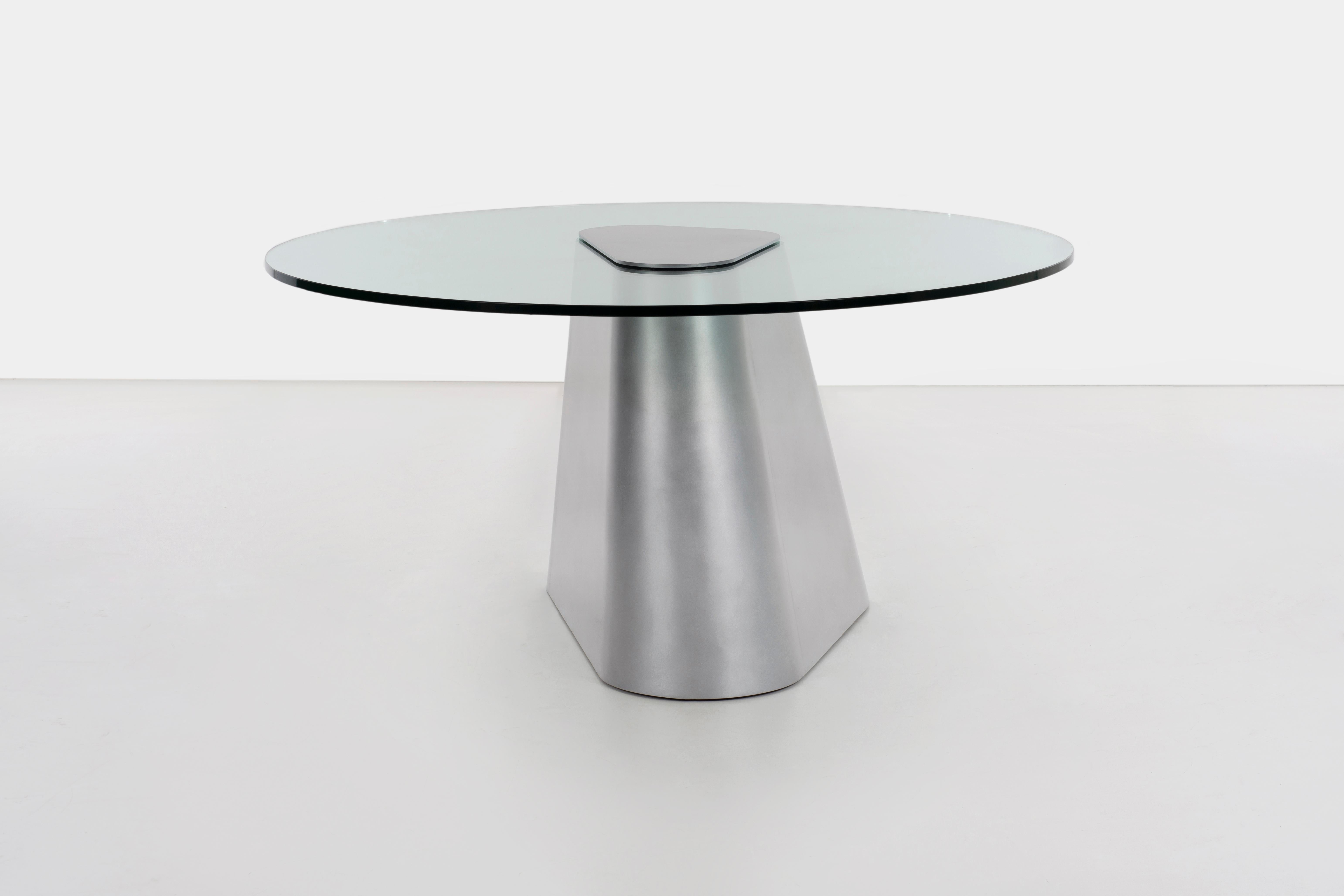 Table TM sculpturale en aluminium poli à la cire avec plateau en verre de 0,75 pouce d'épaisseur. La forme est composée de deux formes Nesci-Triangle qui s'emboîtent pour former la base de cette table à manger à plateau en verre. Le plateau en verre