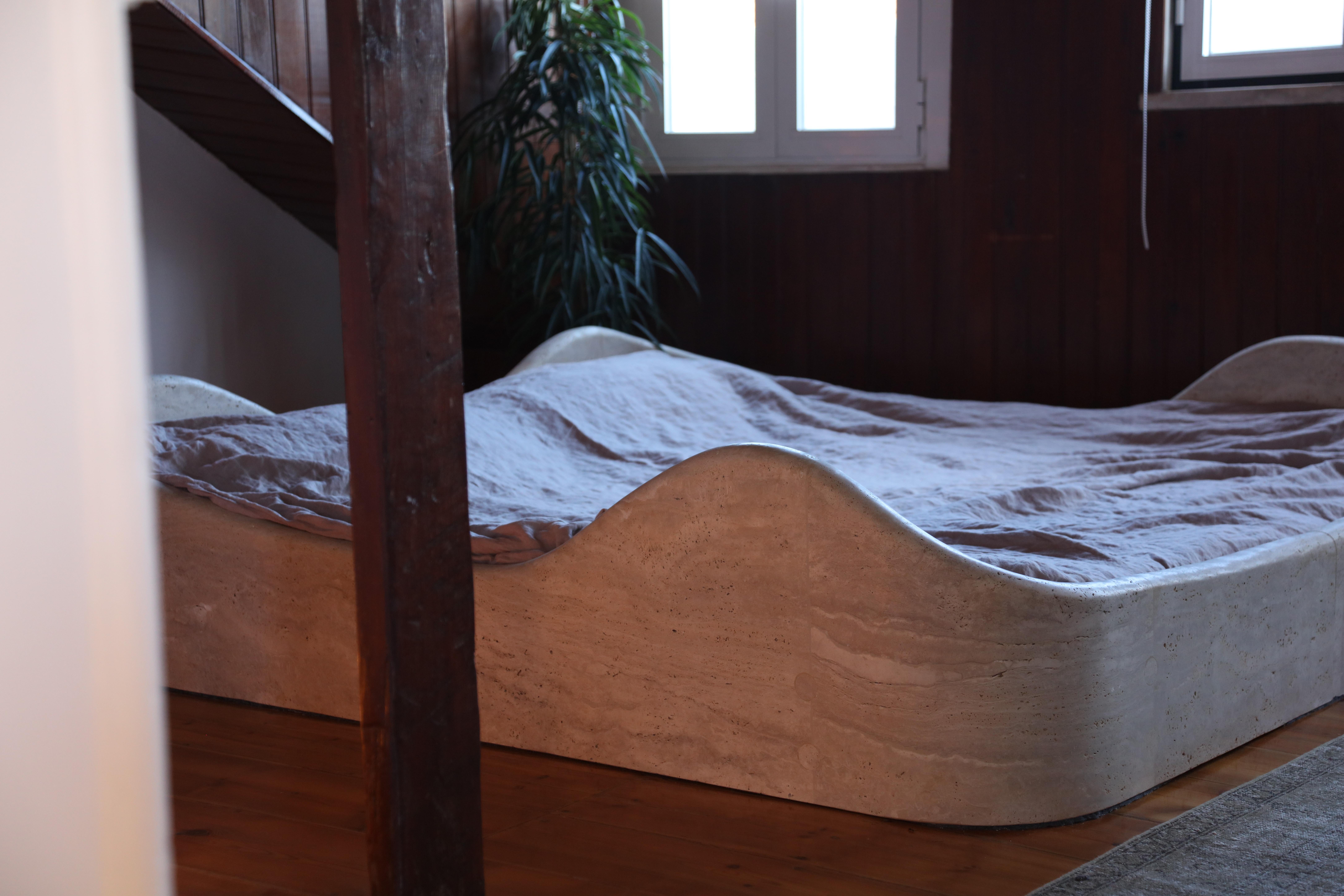 La Cama es una escultural cama baja independiente tallada en travertino, que combina la elegancia arquitectónica con un minimalismo fundamentado. Inspirada en la emblemática cama Anemone de Bernard Govin de los años 70, presenta curvas suaves,