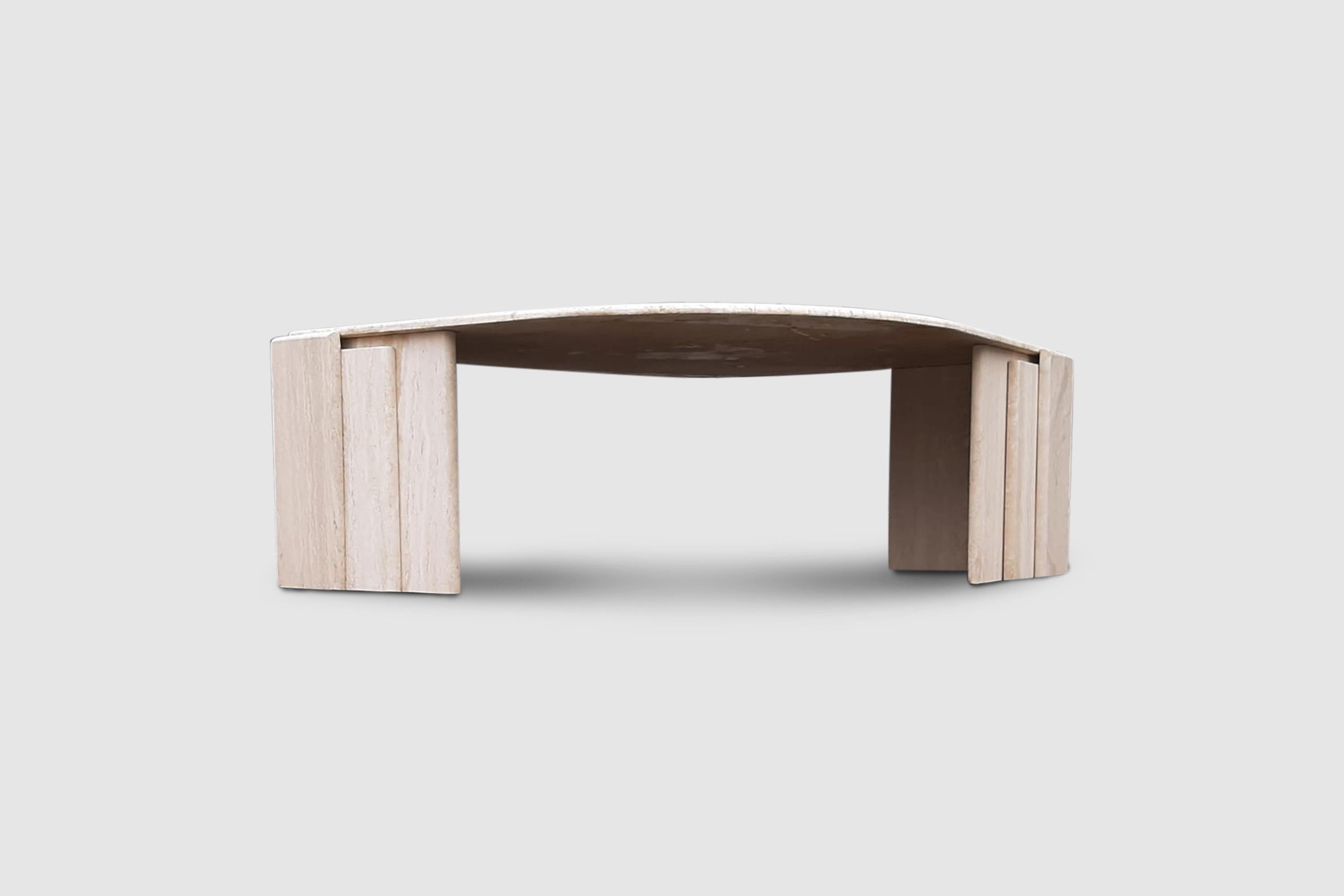 Sculptural travertine marble coffee table in tear shaped form. The table top is supported by 2 sculpted columns.

The marble is a beige travertine, with the natural patterns visible in the material.

The table is very sober in its design but the