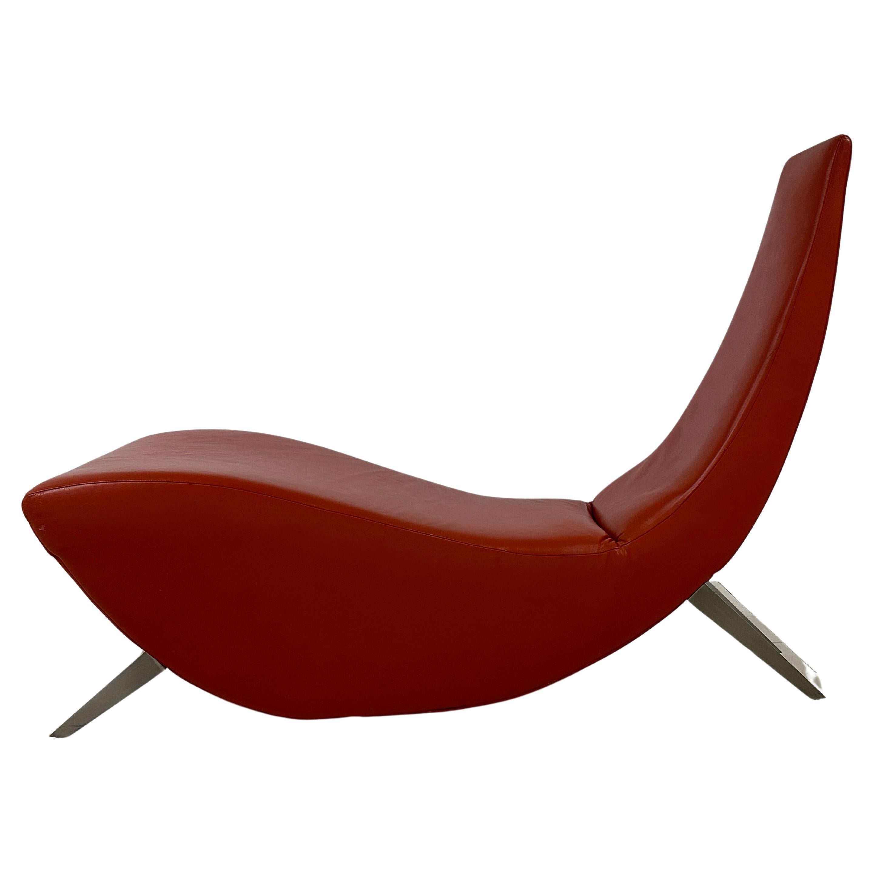 This chaise features a top-notch vermilion leather and 4 brushed steel legs.
It has been made by Stanley Jay Freidman  for Brueton. 
Its sculptural and sleek lines and the quality of the leather testify to the designer's attention to detail and