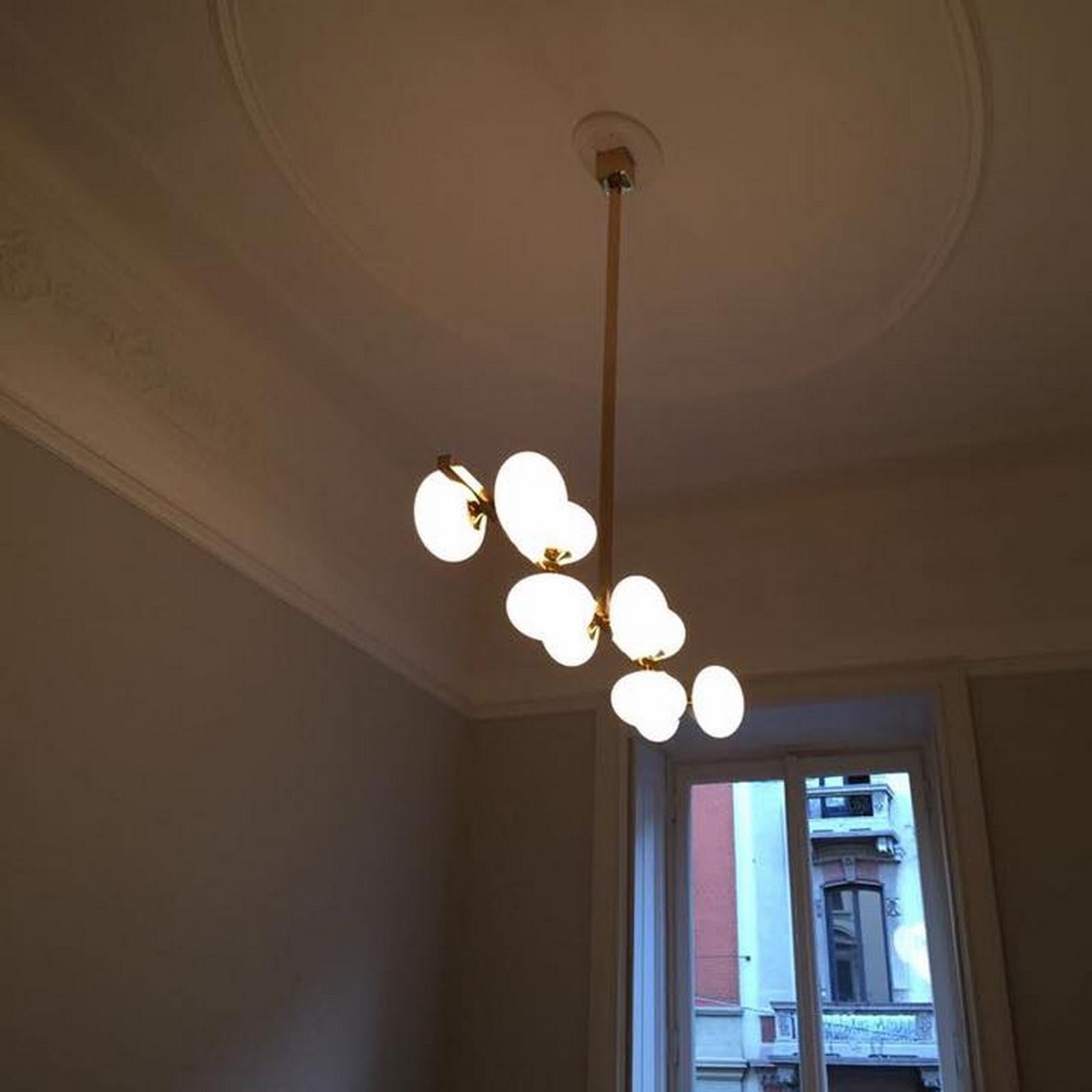 Eleva tu interior con esta lámpara de techo hecha a medida, una sorprendente fusión de sofisticación moderna y elegancia atemporal. Fabricada con latón de primera calidad y globos de cristal soplado a mano, esta luminaria ofrece un diseño