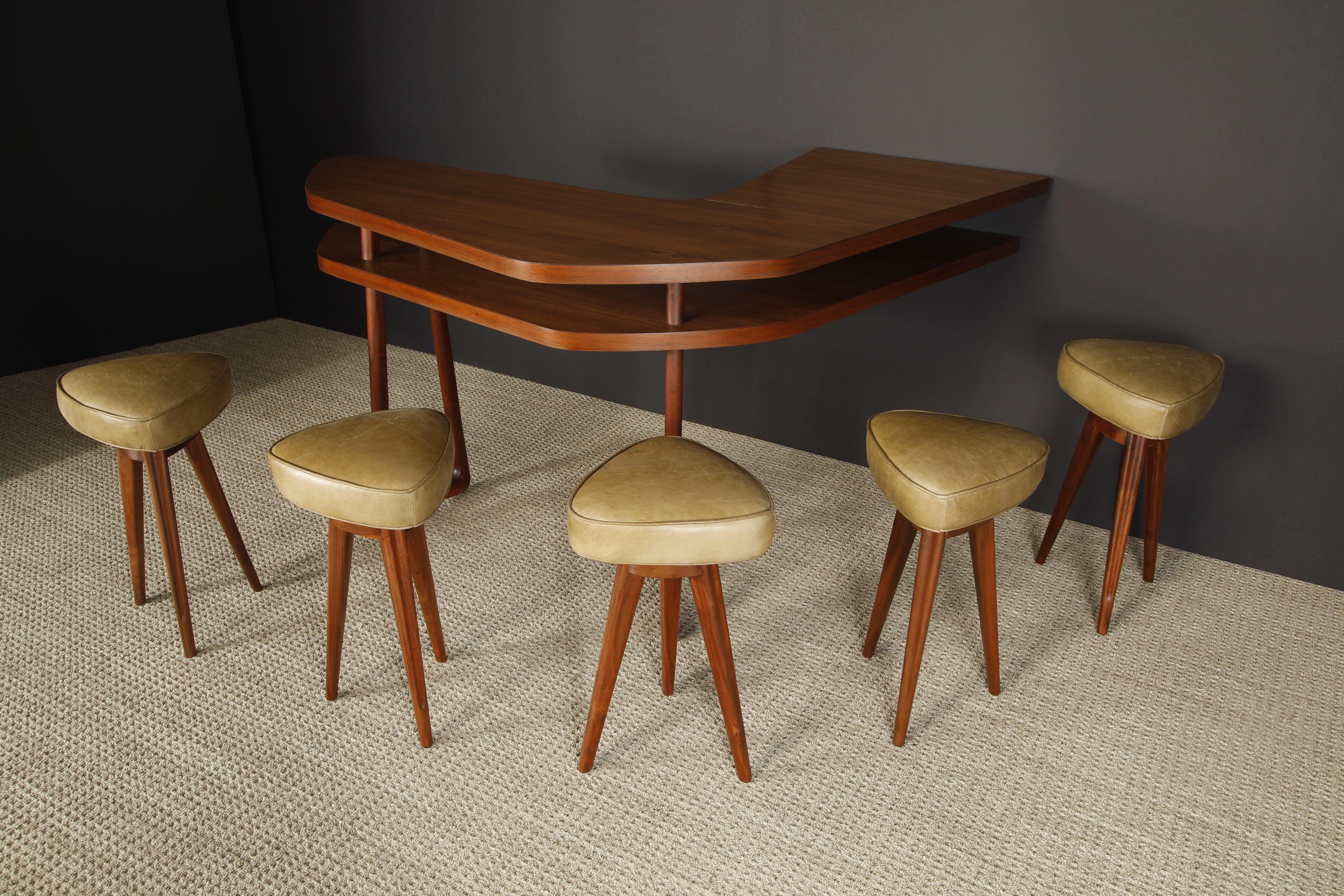 This sculptural boomerang bar with five leather barstools were sculpted from hefty walnut in circa 1950s, attributed to Vladimir Kagan and from a Mid-Century Modern home that had several other confirmed Kagan designs. Freshly refinished and