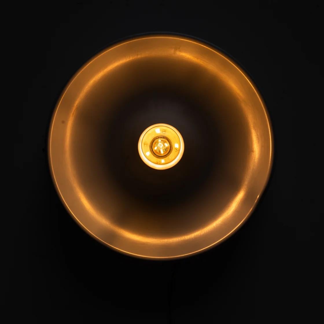 Un aplique de pared minimalista con una forma de cuenco suavemente esculpida y un centro abierto que deja ver la bombilla. Su silueta orgánica y su geometría limpia reflejan la refinada estética de la iluminación decorativa de finales del siglo XX.