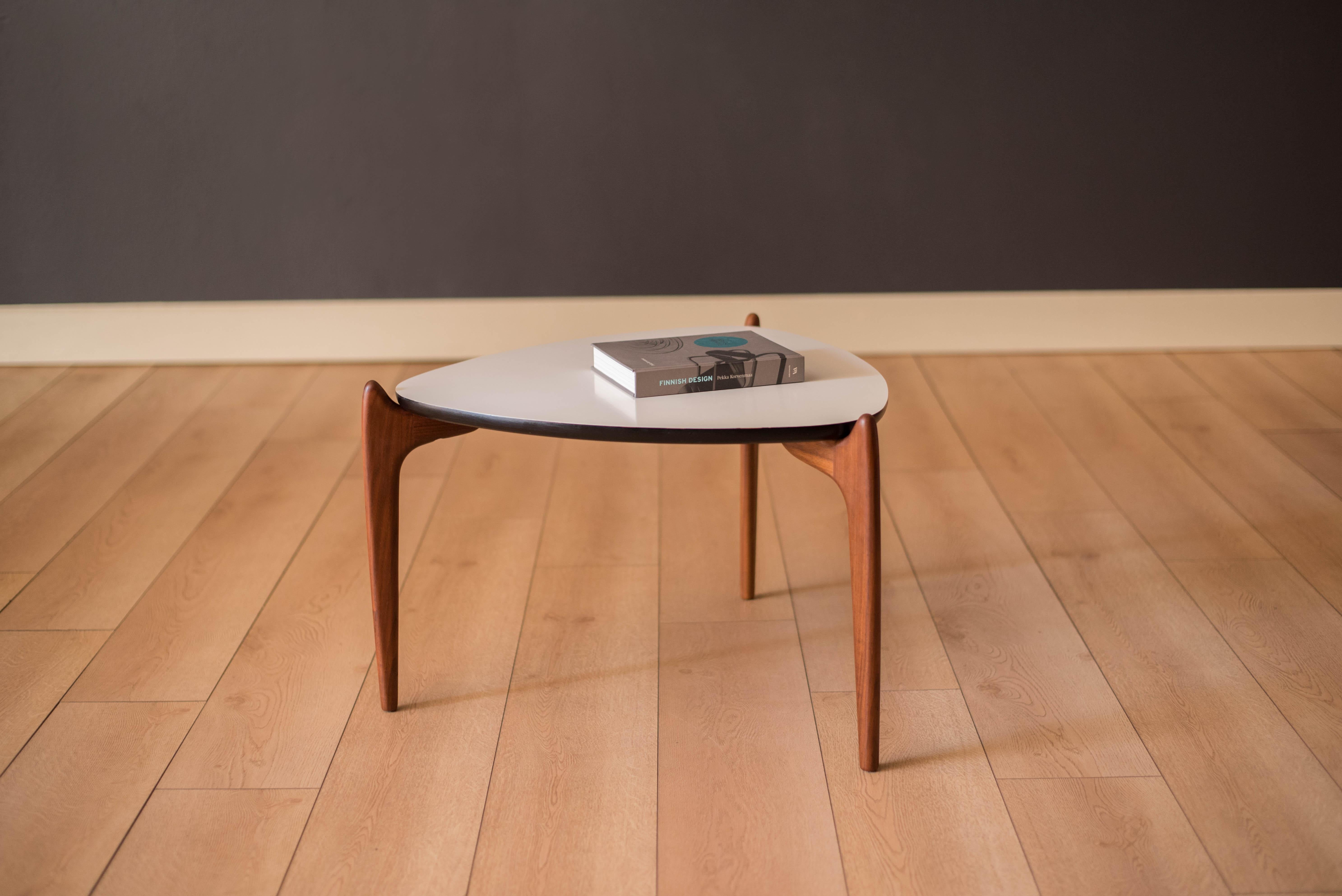 Mid-Century Modern occasional triangle coffee table or accent end table designed by Adrian Pearsall for Craft Associates, c. 1960's. This piece features a contrasting white laminate table top supported by three sculptural solid walnut legs. Easy to