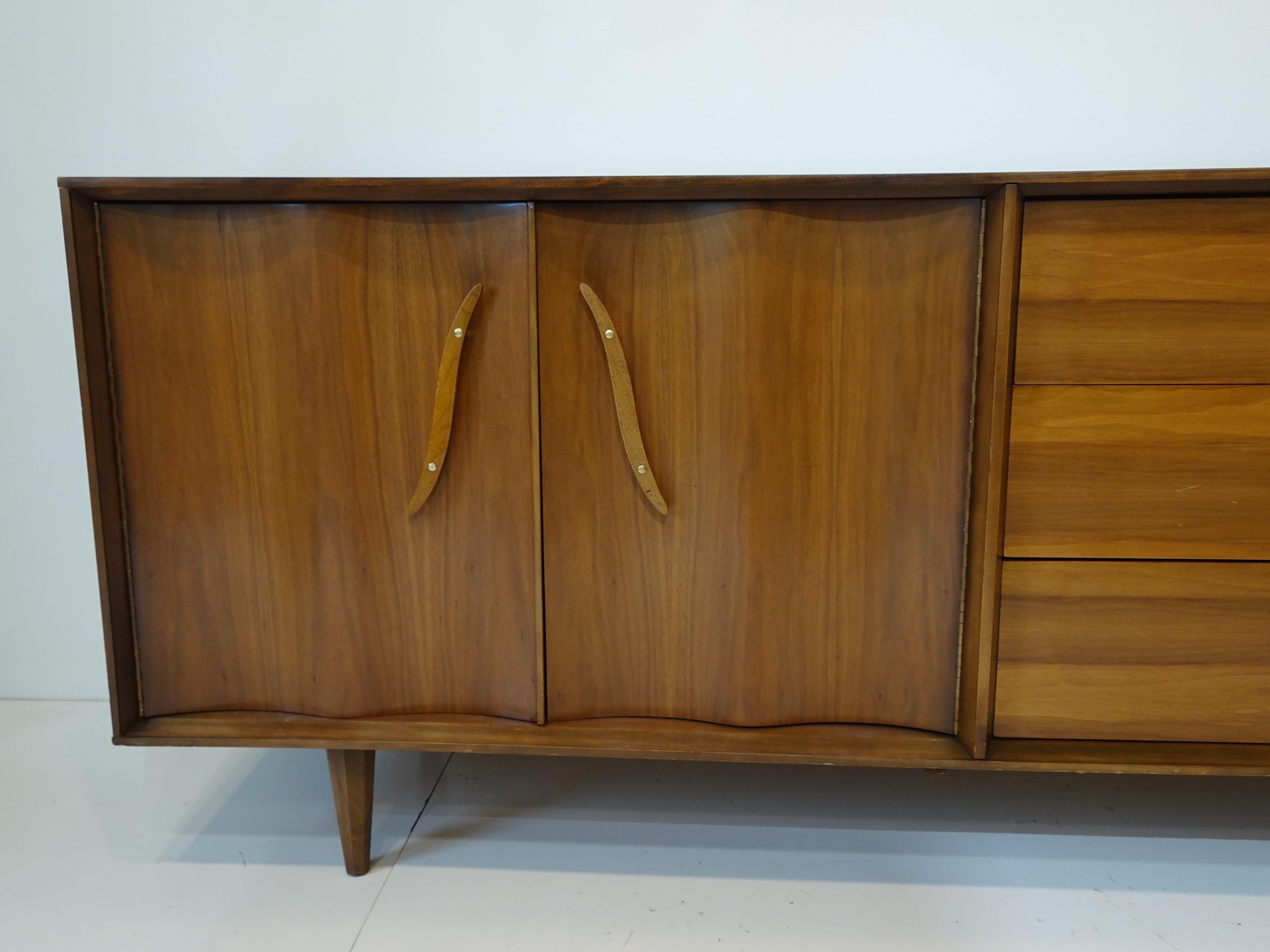 A very well crafted walnut dresser chest with double scalloped doors to one side with three walnut drawers , the other side has three larger drawers . The doors and side drawers have nice sculptural handles with brass detail mounting studs , retains