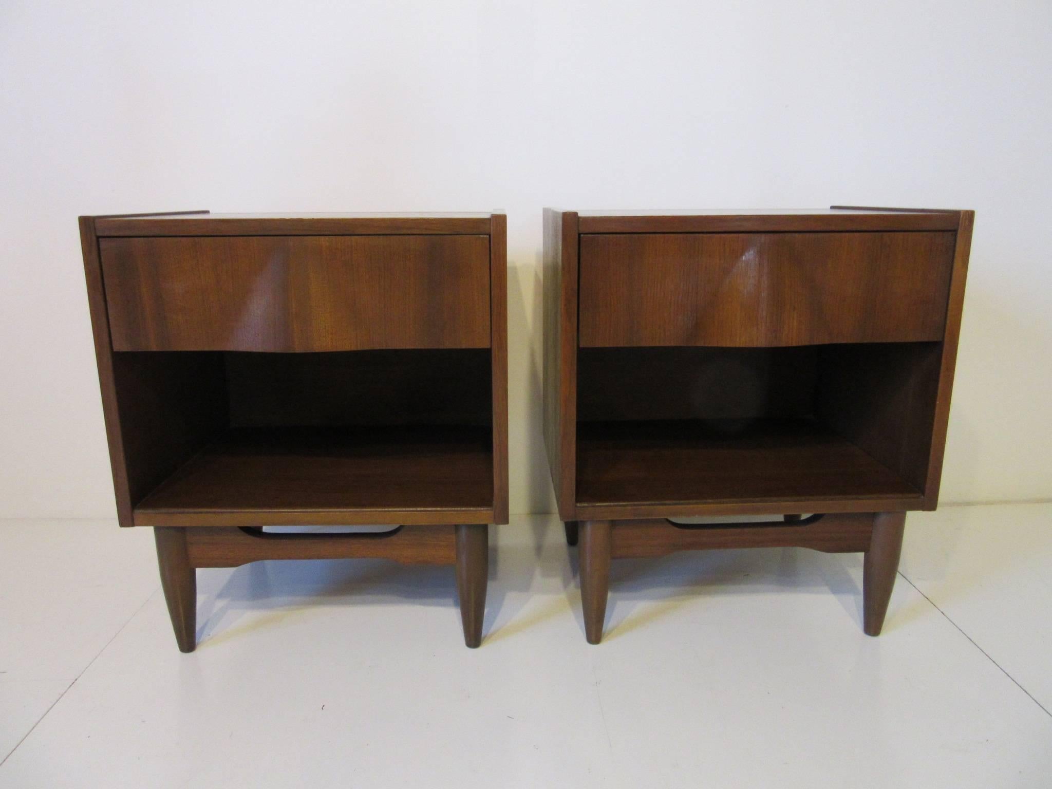 A pair of well grained walnut nightstands with single drawers, storage and the pull area has a sculptural front design making them quite attractive.