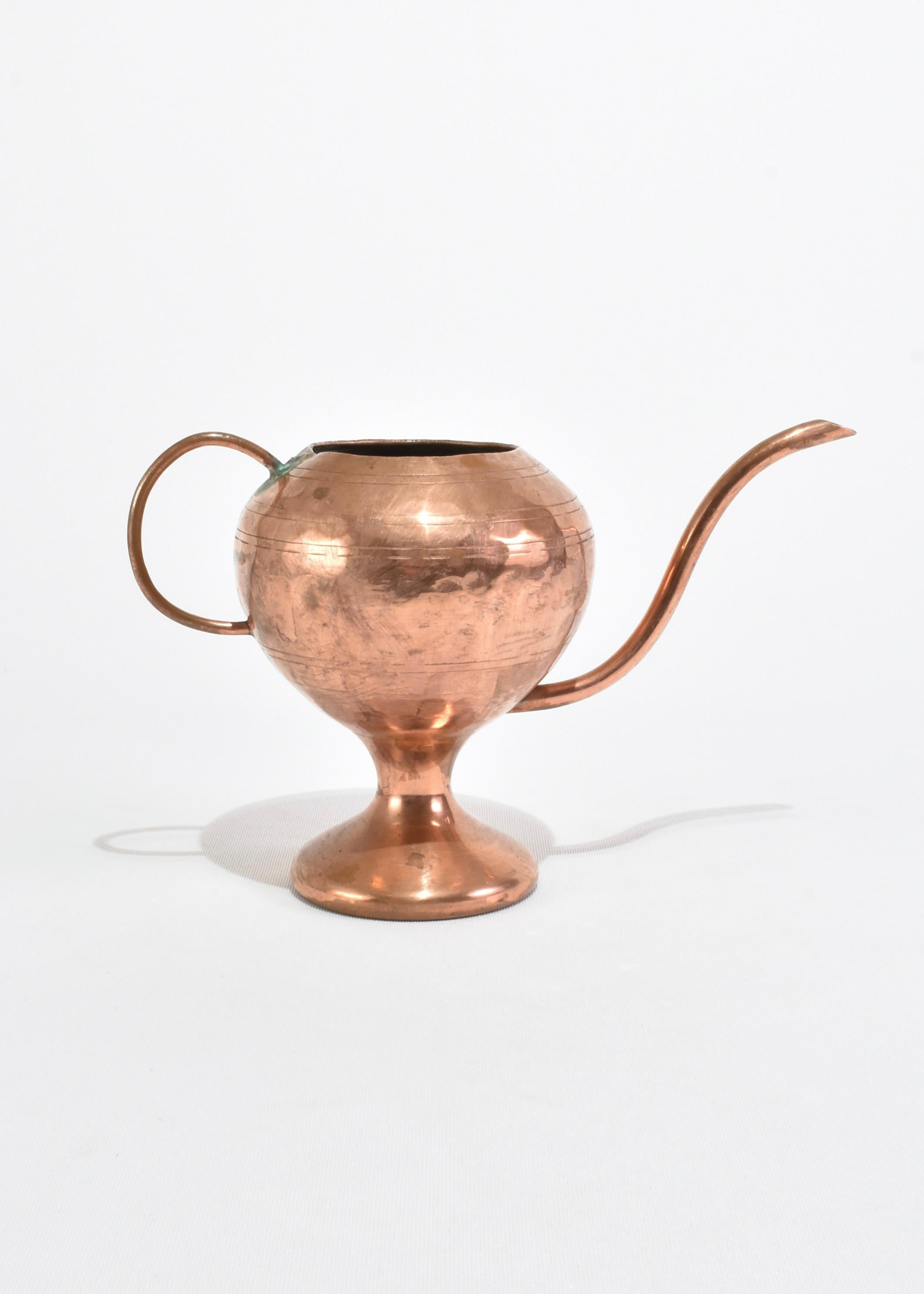Sculptural vintage watering can with a handle and elongated spout in copper.