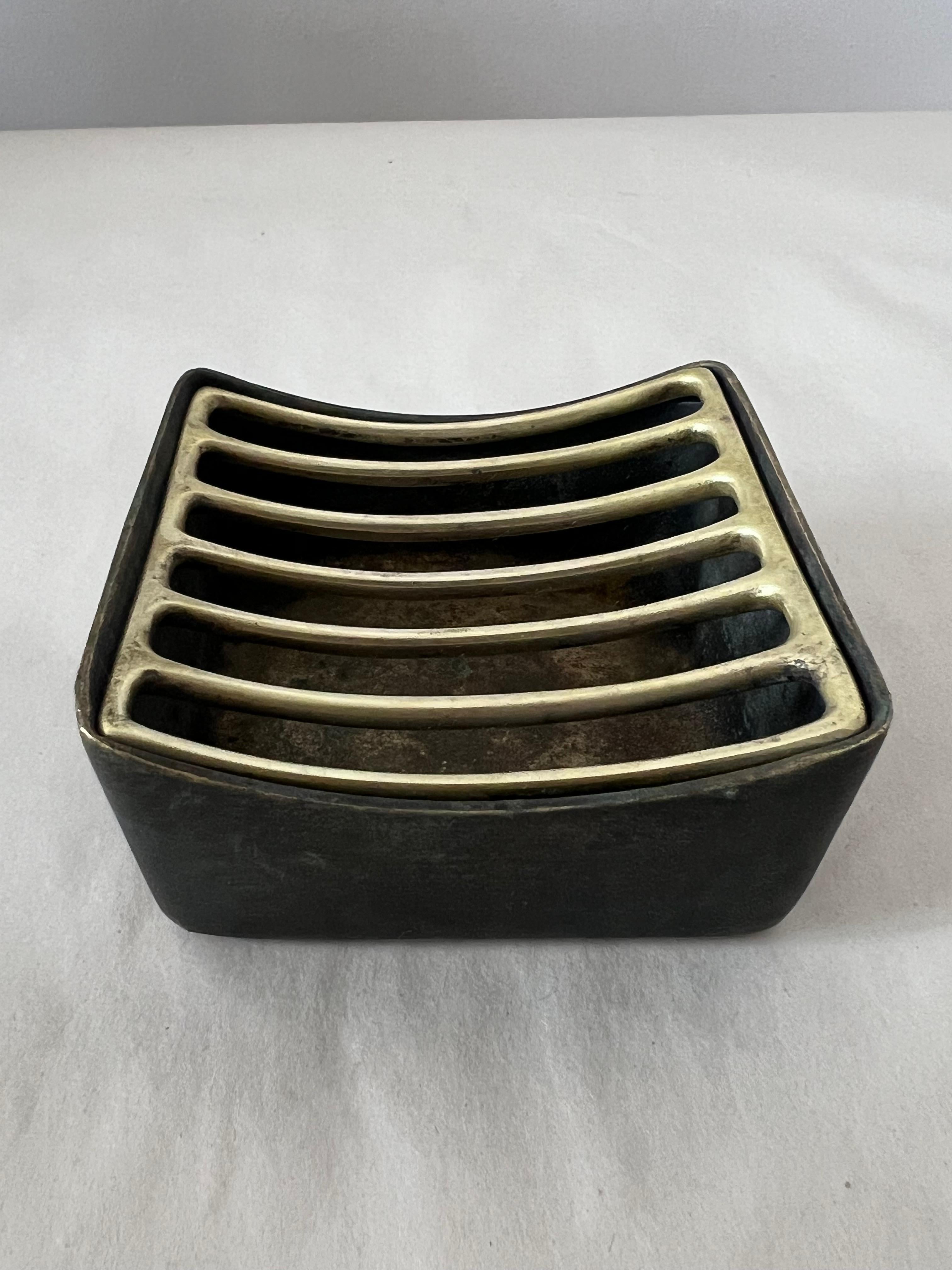 Magnifique cendrier du milieu du siècle, exécuté dans les années 1950 par Werkstätte Hagenauer, Autriche, en très bon état avec une belle patine. Grille supérieure amovible. SignéWerkstätte Hagenauer Cendrier moderniste en laiton, Autriche, années