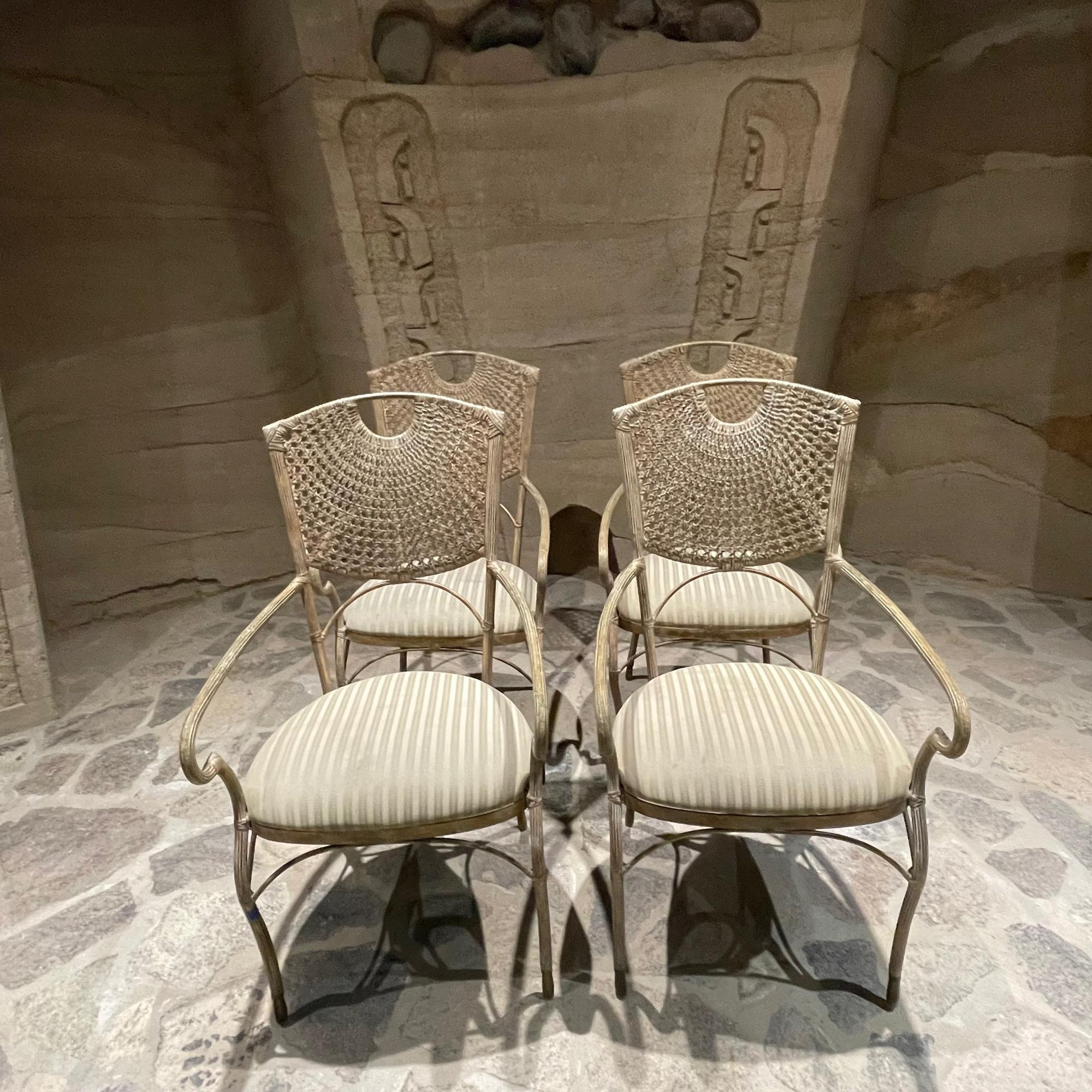 Ensemble de quatre chaises de salle à manger sculpturales en rotin tressé à la main avec dossier en treillis 
Cadre en fer. Une étonnante élégance de style régence.
pas de Label.
Dans le style de Maitland Smith et McGuire. 
Conserve la sellerie