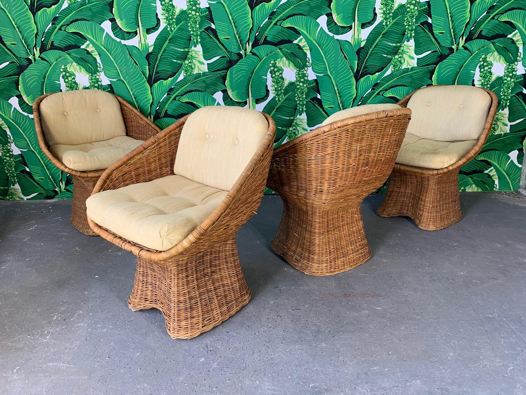 Set of four sculptural wicker dining chairs feature unique draped pedestal and scoop shape seat. Cream fabric in good condition. Wicker in very good condition.