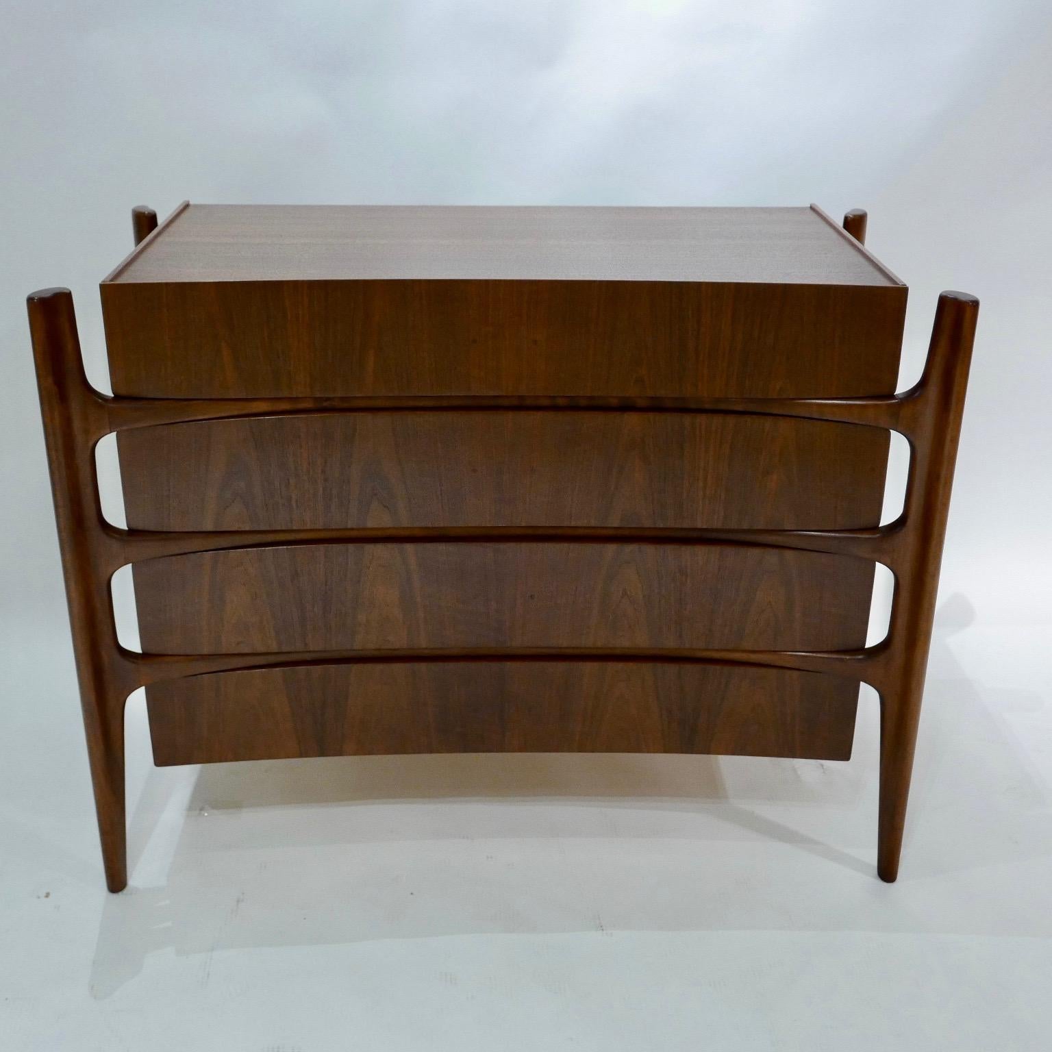 Exposed carved walnut legs with a curved bookmatched walnut front. Beautiful and Sculptural four draws dresser designed by William Hinn for Urban Furniture's 