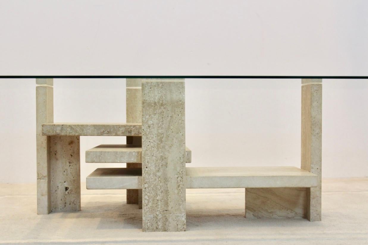 Stunning graphical Belgian coffee table with glamorous performance. Designed and handcrafted by Willy Ballez in the 1970s. The heavy base is built in blocks of travertine and has a very nice Graphical effect. The form changes from every perspective.