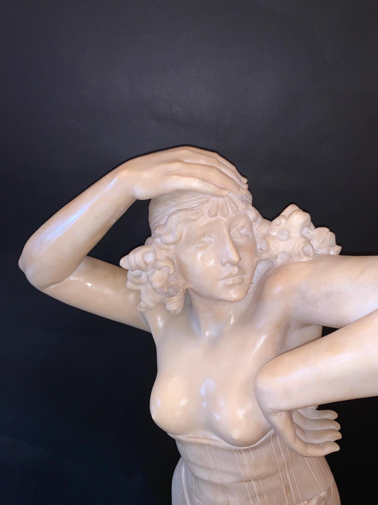A marble figurative sculpture of a woman and torchère.