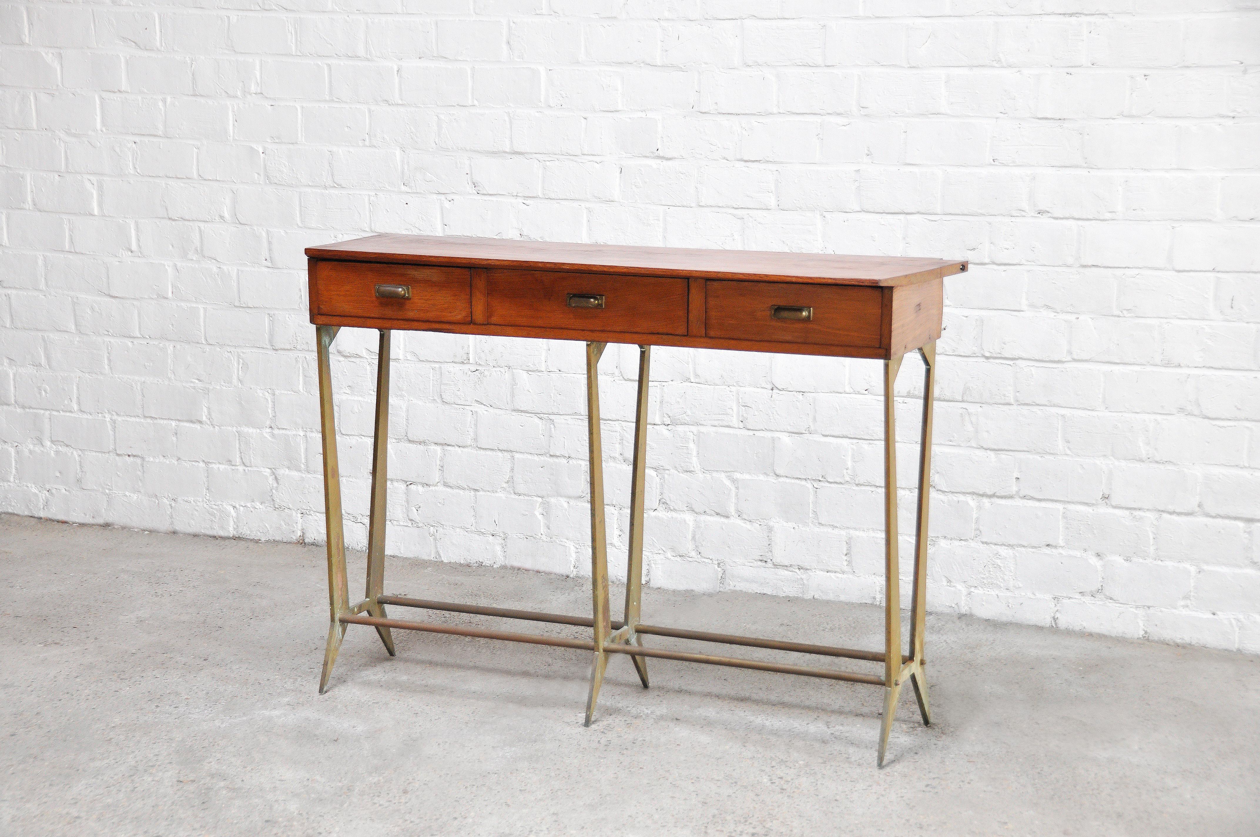 Sculptural wood and brass console table with X-shaped legs, made in Italy in the 1950s. The style is reminiscent of the work of Osvaldo Borsani. This console features a wooden top with three drawers for storage. The top is cut at an angle for a