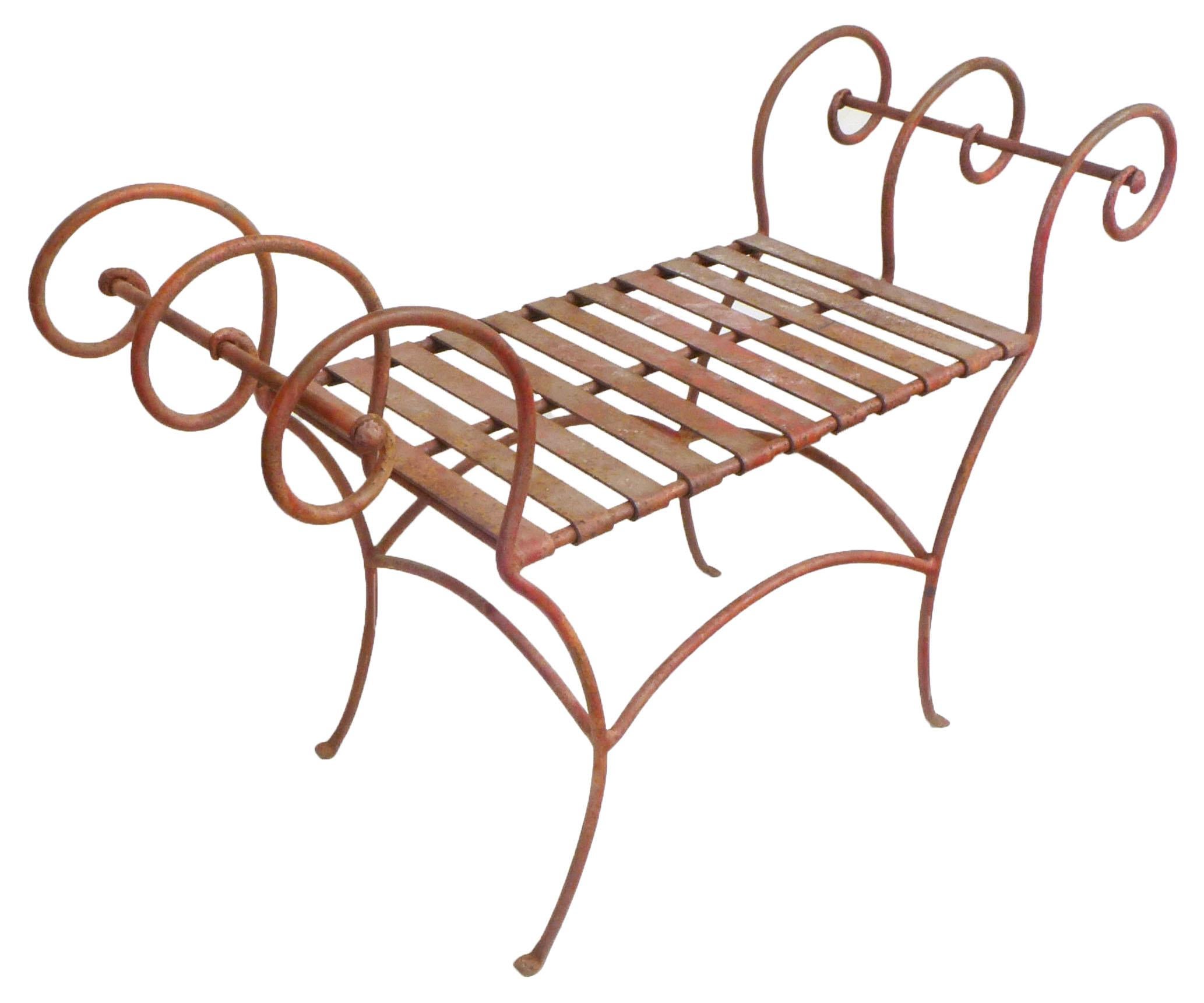 A wonderfully sculptural wrought iron bench, with scrolling armrests and a flat-band seating surface. This elegant seating accent piece retains its original and beautifully patinated red-painted finish. A very decorative, almost Royère-like
