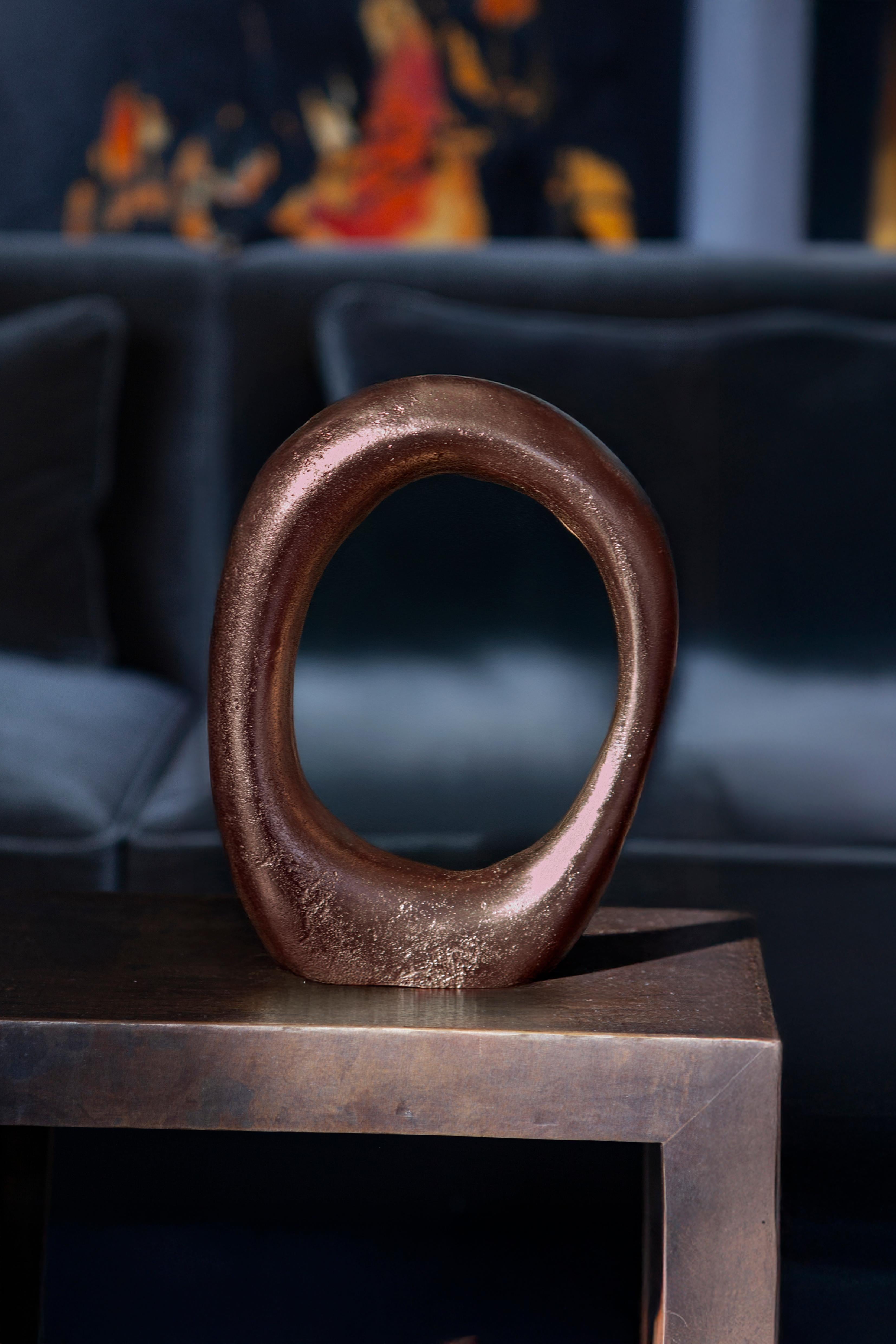 La scultura Fluid Series, realizzata con la tecnica del sand-casting, presenta una silhouette ad anello che cattura il dolce flusso della liquidità congelata nel tempo. La sua forma circolare e continua, priva di un inizio o di una fine, invita alla