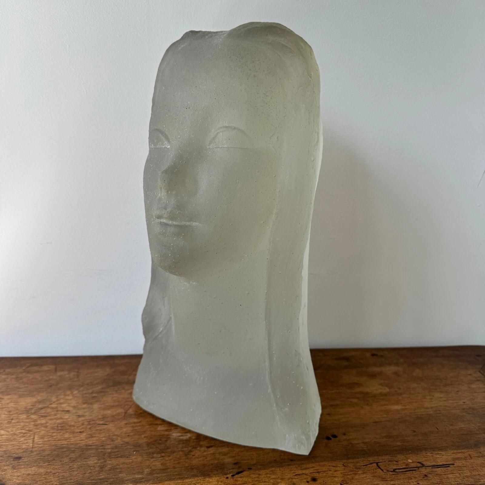 This piece strongly reminds us of Lucien Lafaye (1895–1976), although the sculpture bears no signature. It is made of molded glass and depicts a delicate female face. 
The entire piece is quite heavy.
As for its condition, we note three internal