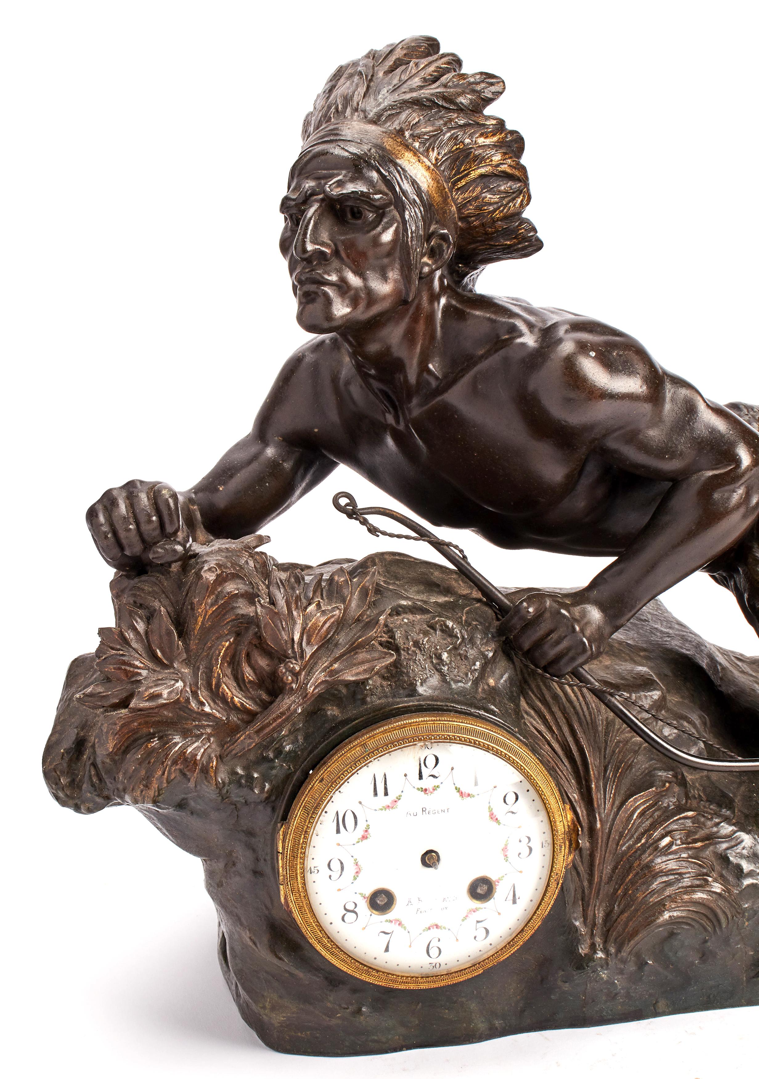 A metal sculpture clock, with original patina, depicting a native American chief with a bow, laying down over a rock, ambushing. France, circa 1890.