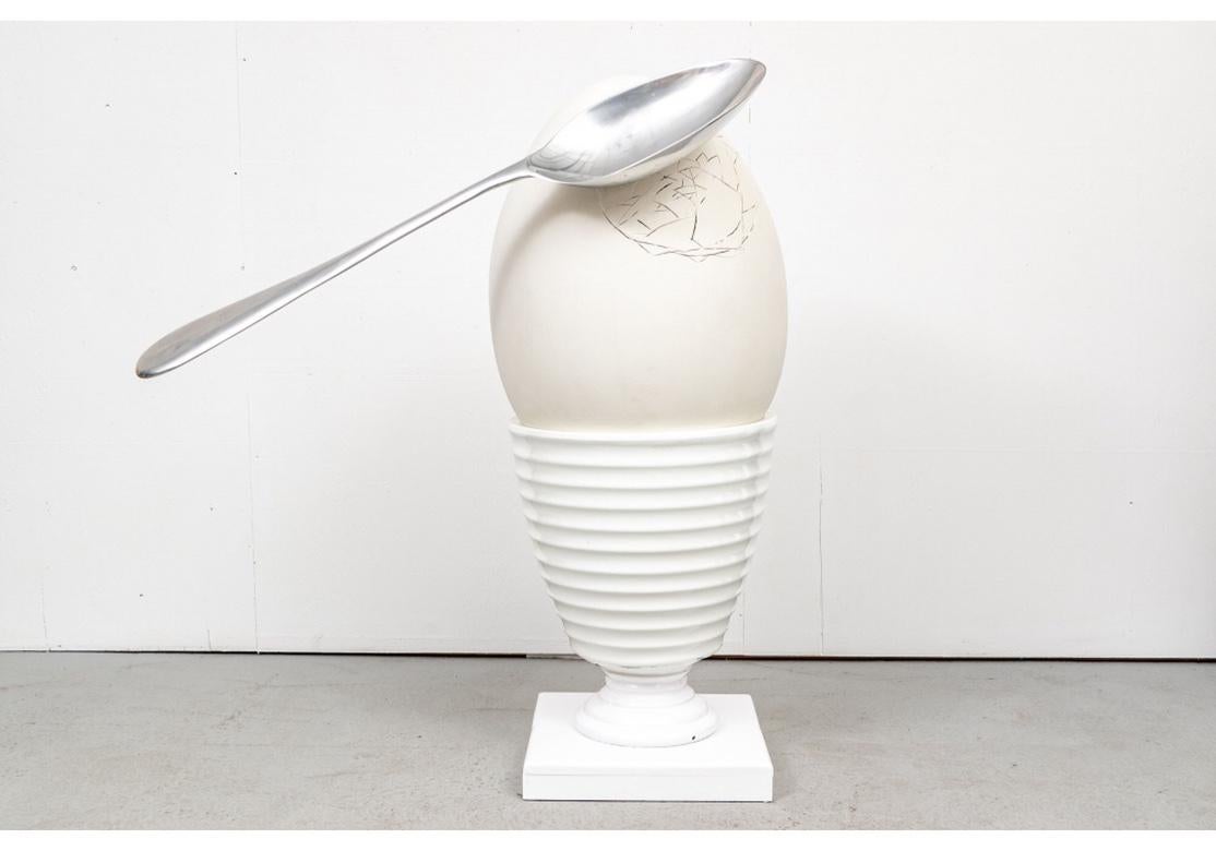 A very large and Surreal fiberglass and acrylic paint sculpture by Artists Debbie Millman and Kevin O’Callaghan depicting a cracked soft boiled egg and it’s accompanying spoon. This Sculpture was part of a celebrated art event which was put on by