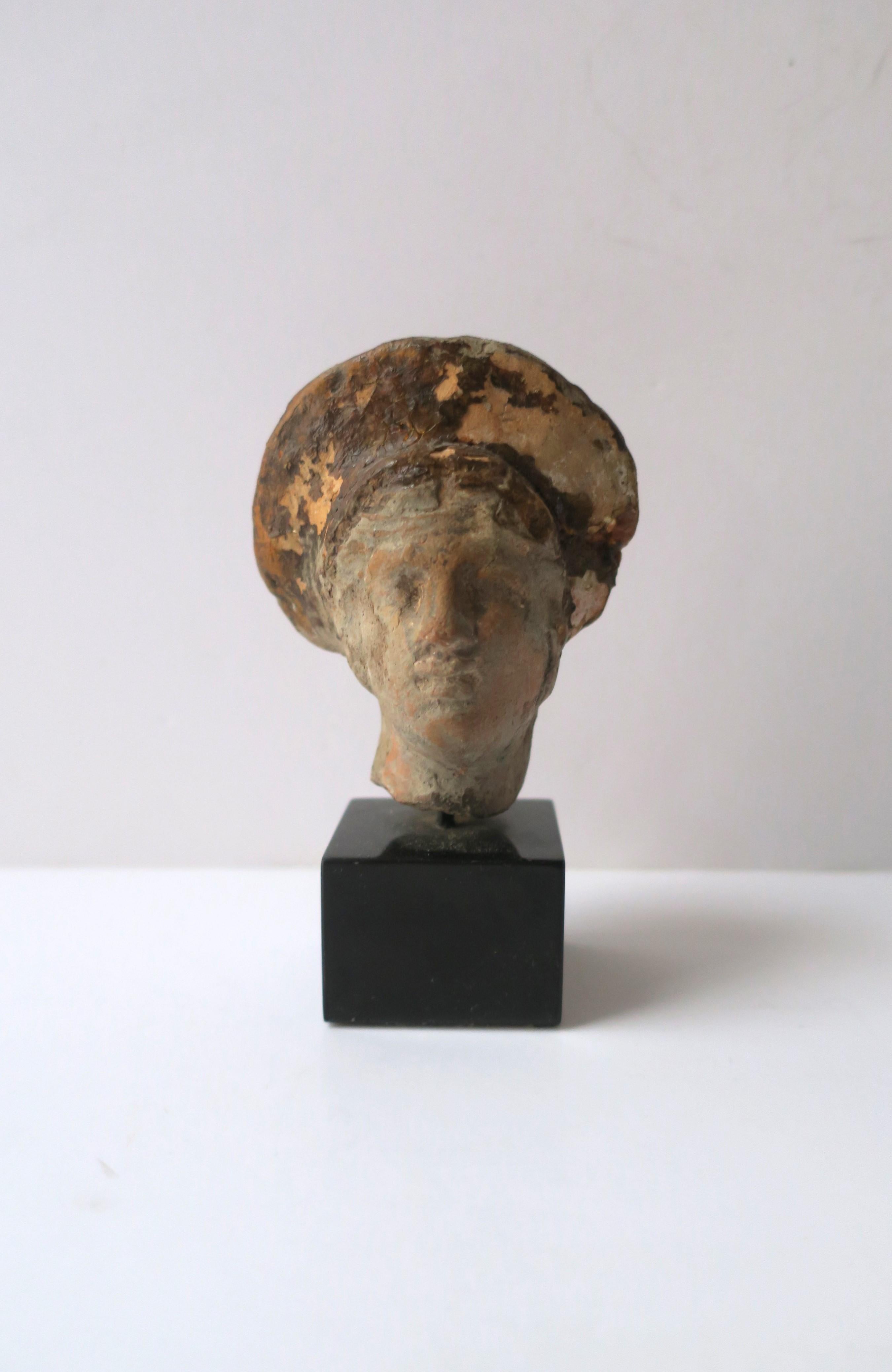 A hand-crafted terracotta head bust sculpture of a Greek Goddess on a black Belgium marble base, Europe, Greece, circa early-20th century or earlier. Exact date unknow. Artist/Sculptor unknown. This beautiful sculpture may work well on an end table,