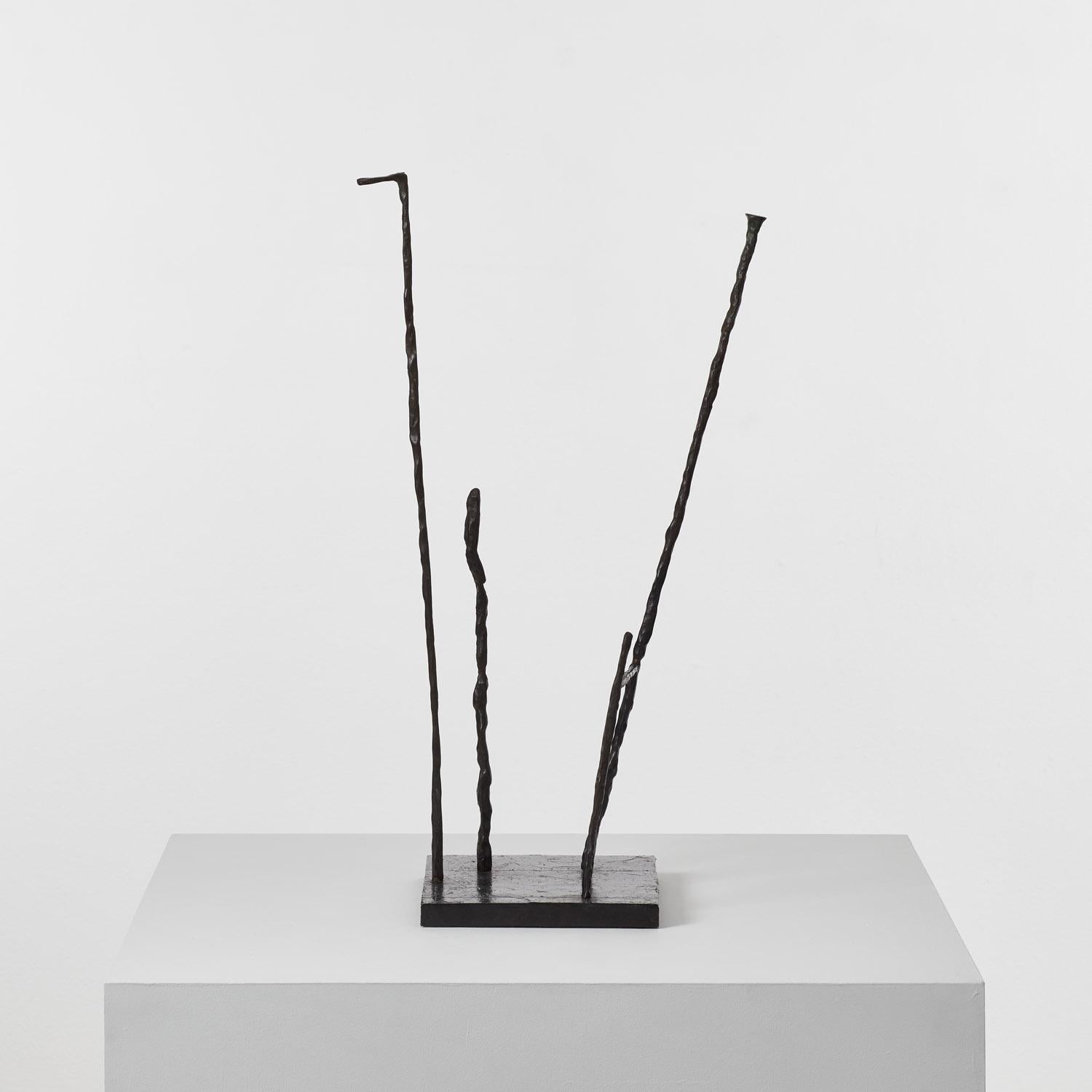 Four rods of iron rise from a square plinth. Designed to be viewed in the round, the sculpture reveals ever-shifting compositions of intersecting lines and shapes that emerge in negative space. The iron rods are rationalist and spare in form but