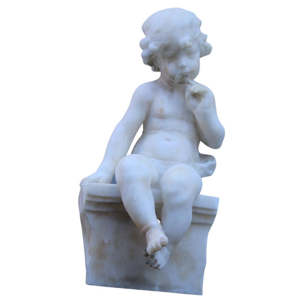 Sculpture en albâtre blanc de 1910 représentant un enfant assis sur un mur réfléchissant