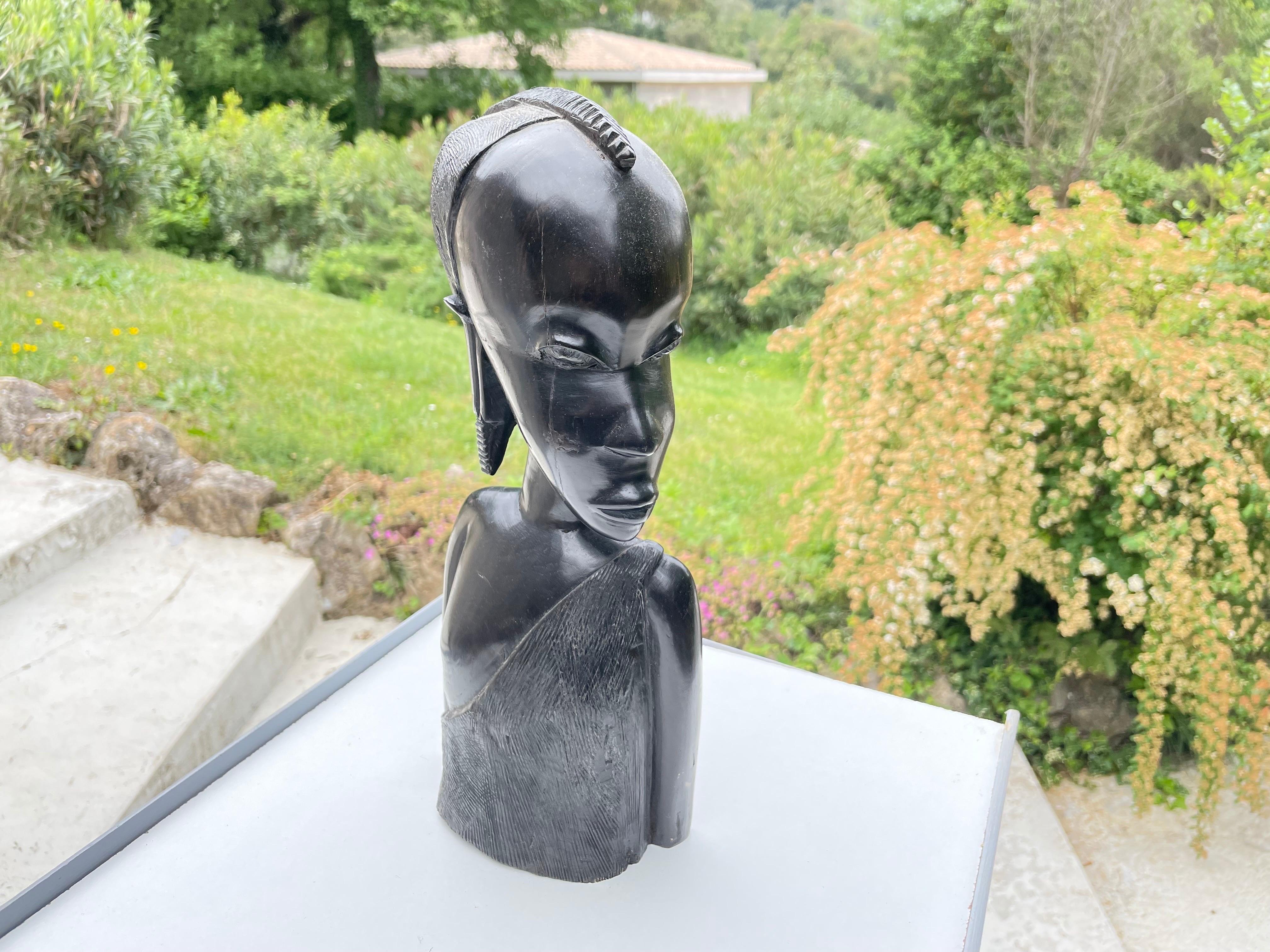 Cette sculpture est un buste de femme, avec sa coupe aérienne traditionnelle. Il est en bois, de couleur noire, et a été fabriqué en Afrique dans les années 1960.