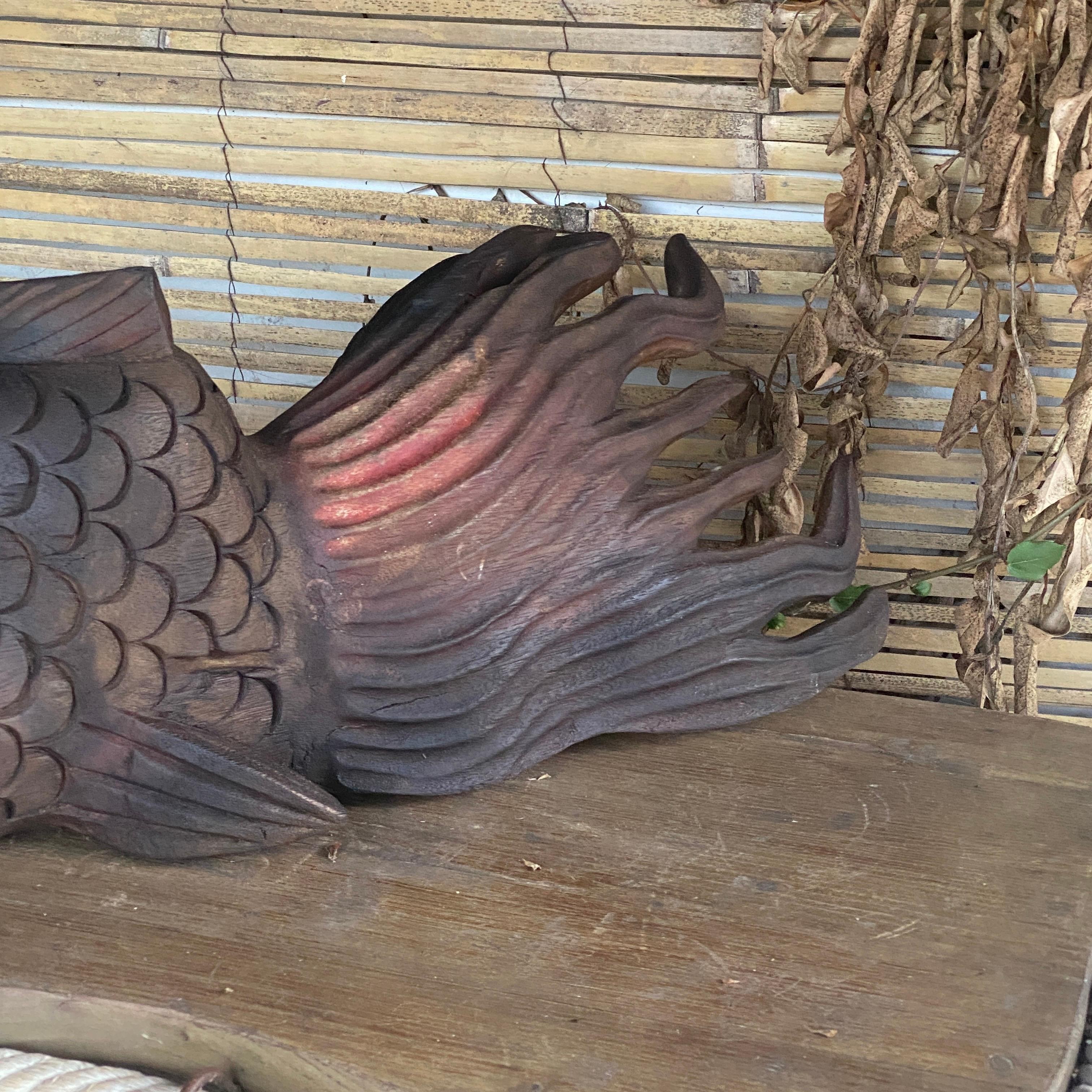 This Sculpture is in Wood, representing a Fish, in a dark brown color, with red color. It has been made in France circa 1970.