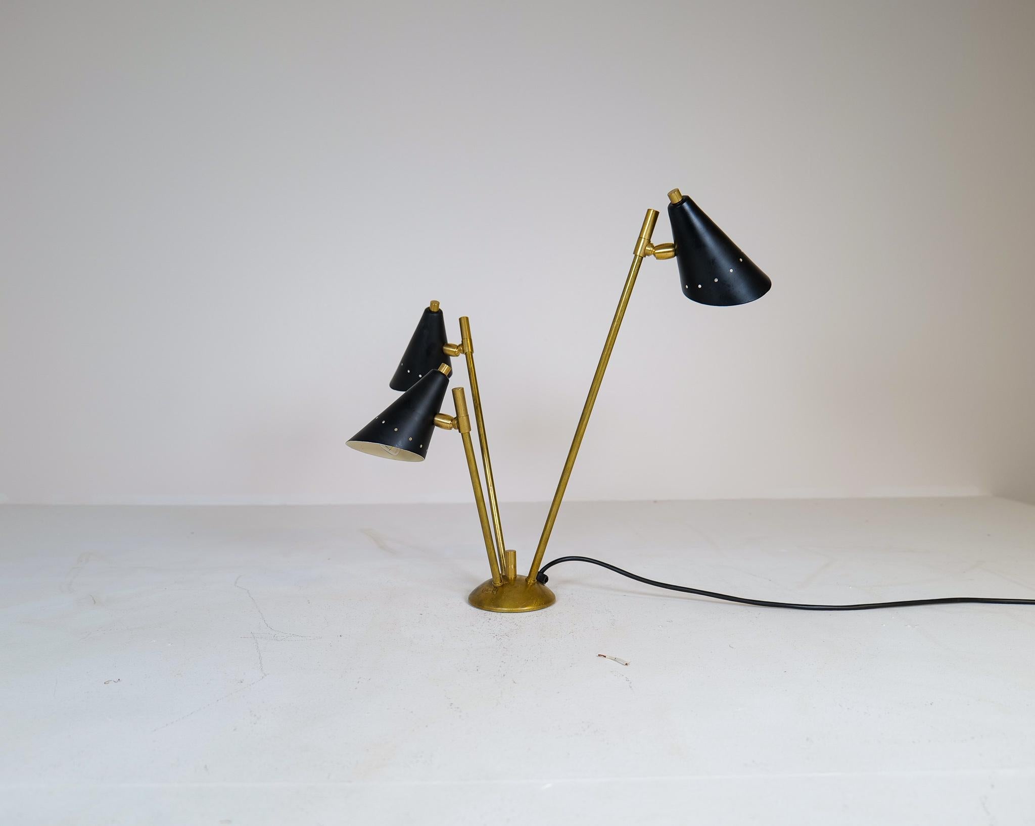 Wonderful Italian modern table lamp. This sculptural lamp has three light sources with. Made with brass and painted sheet metal. Lampshades are adjustable and can light in different directions. 

Good vintage condition, brass with some