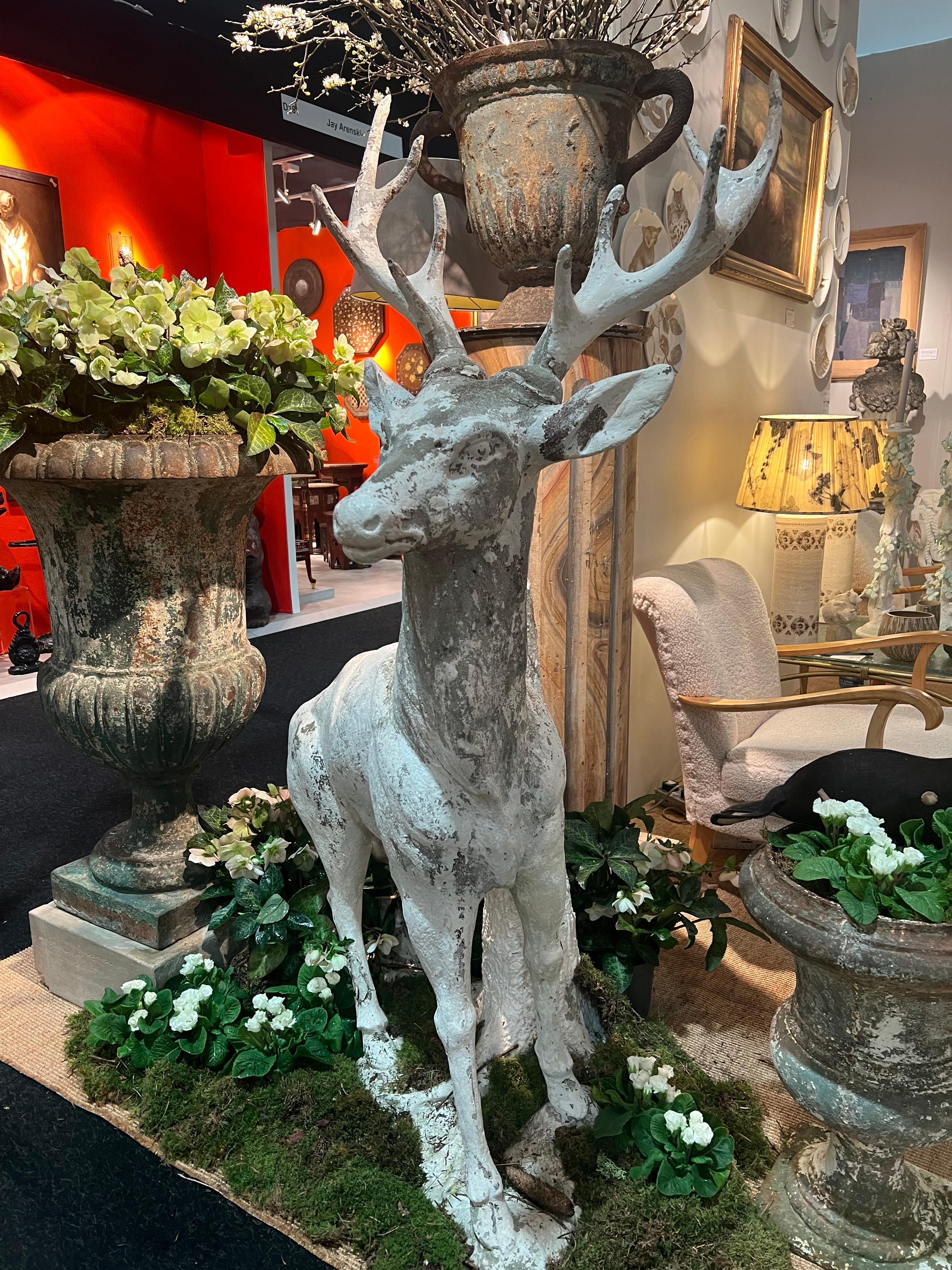 Cast Sculpture of a stag in white painted cement standing against a tree trunk For Sale