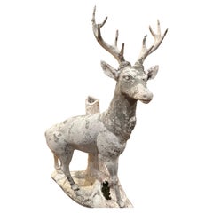 Sculpture d'un cerf en ciment peint en blanc debout sur un tronc d'arbre