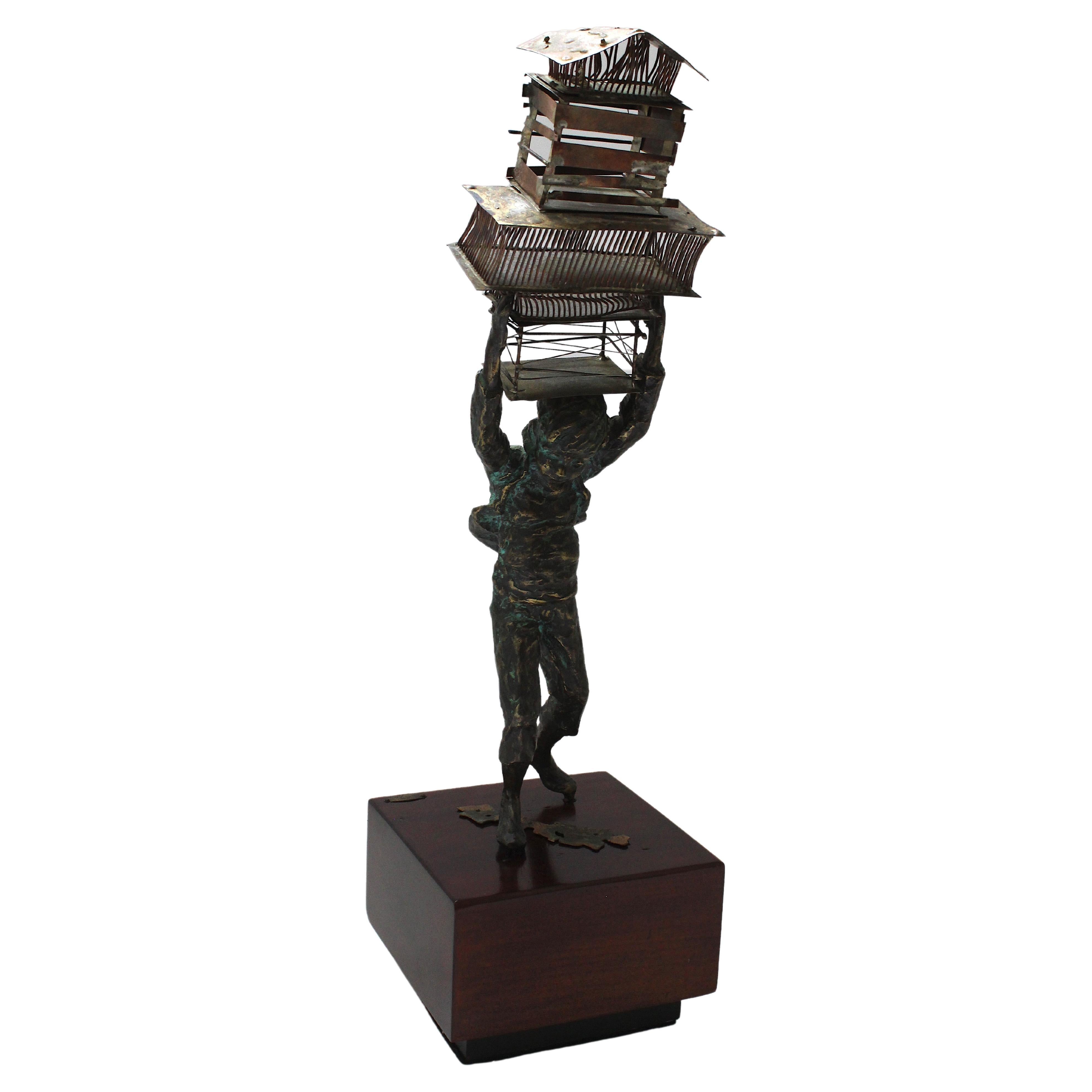 This stylish, chic, and charming sculpture of a young man balancing bird cages upon his head dates to 1972, and it was created by Curtis & Jere.  

Note: The piece detaches from the base.