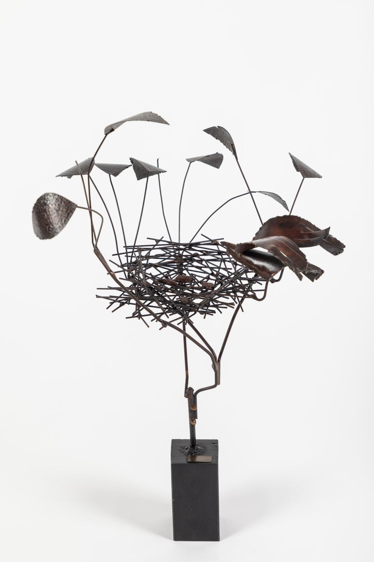 Wonderful sculpture fixed to a weighted iron base. There is a stylized “tree” in steel with leaves, centered is a bird’s nest with brass eggs and a brass bird hovering over the nest. There is a brass plaque on the bass and is signed with the