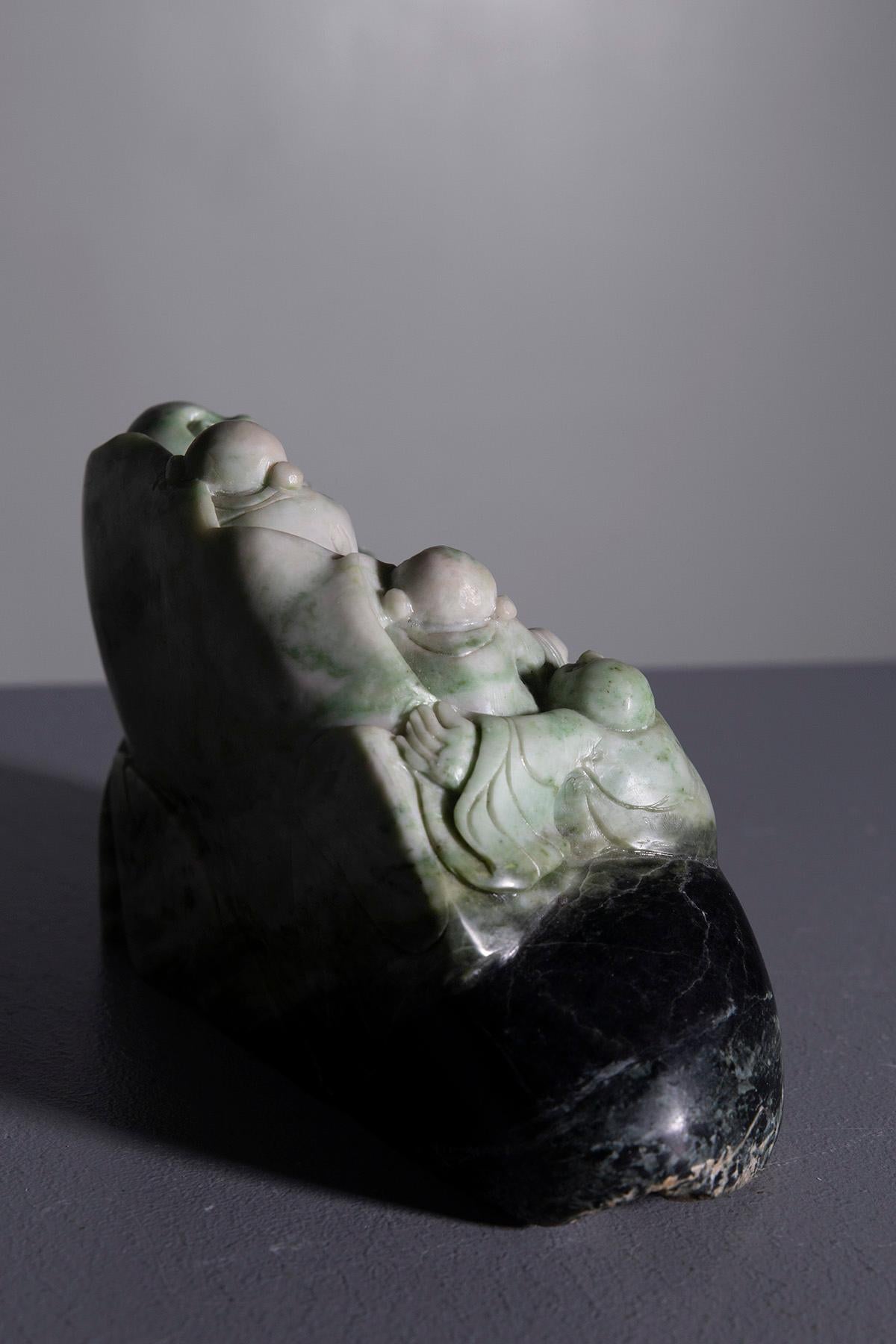 Esta escultura de raíz de jade representa a un Buda Feliz rodeado de una multitud de niños alegres. Cada detalle está meticulosamente tallado, resaltando expresiones serenas y alegres que simbolizan la abundancia y la protección. El Buda, con su