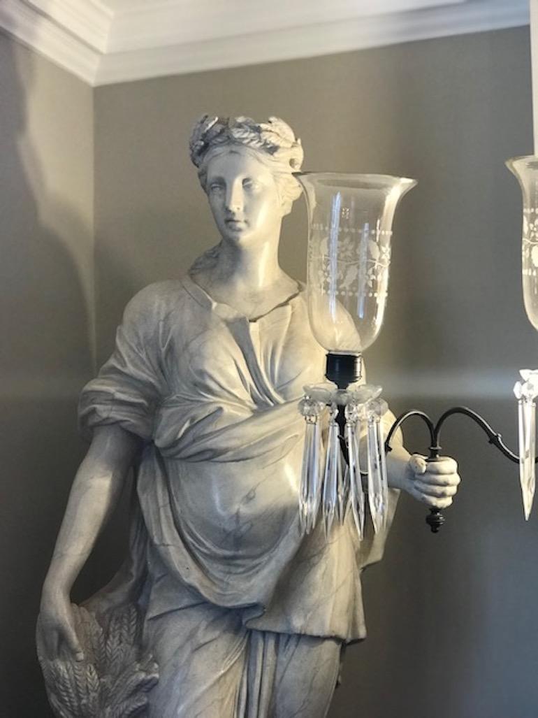 Sculpture of classical figure (possibly Greek Goddess Demeter considering the wheat details) with a pair of glass lamps.

Painted plaster, circa 1880-1900.

Measures: Height, 167cm
Width (at widest point including the glass lamps), 67cm
Depth