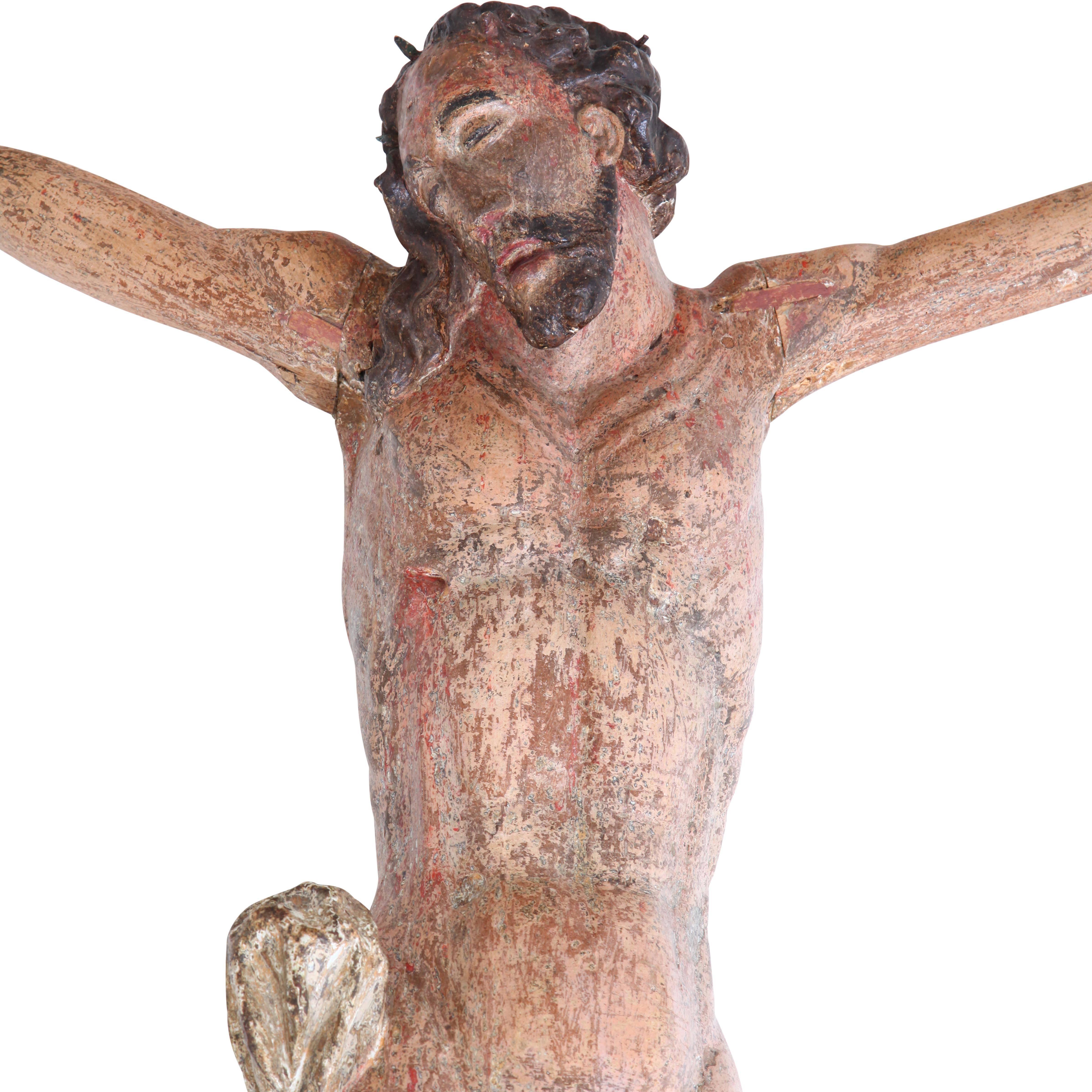Sculpture of Jesus Christ on a Cross with white loincloth. The paint shows partly wear.