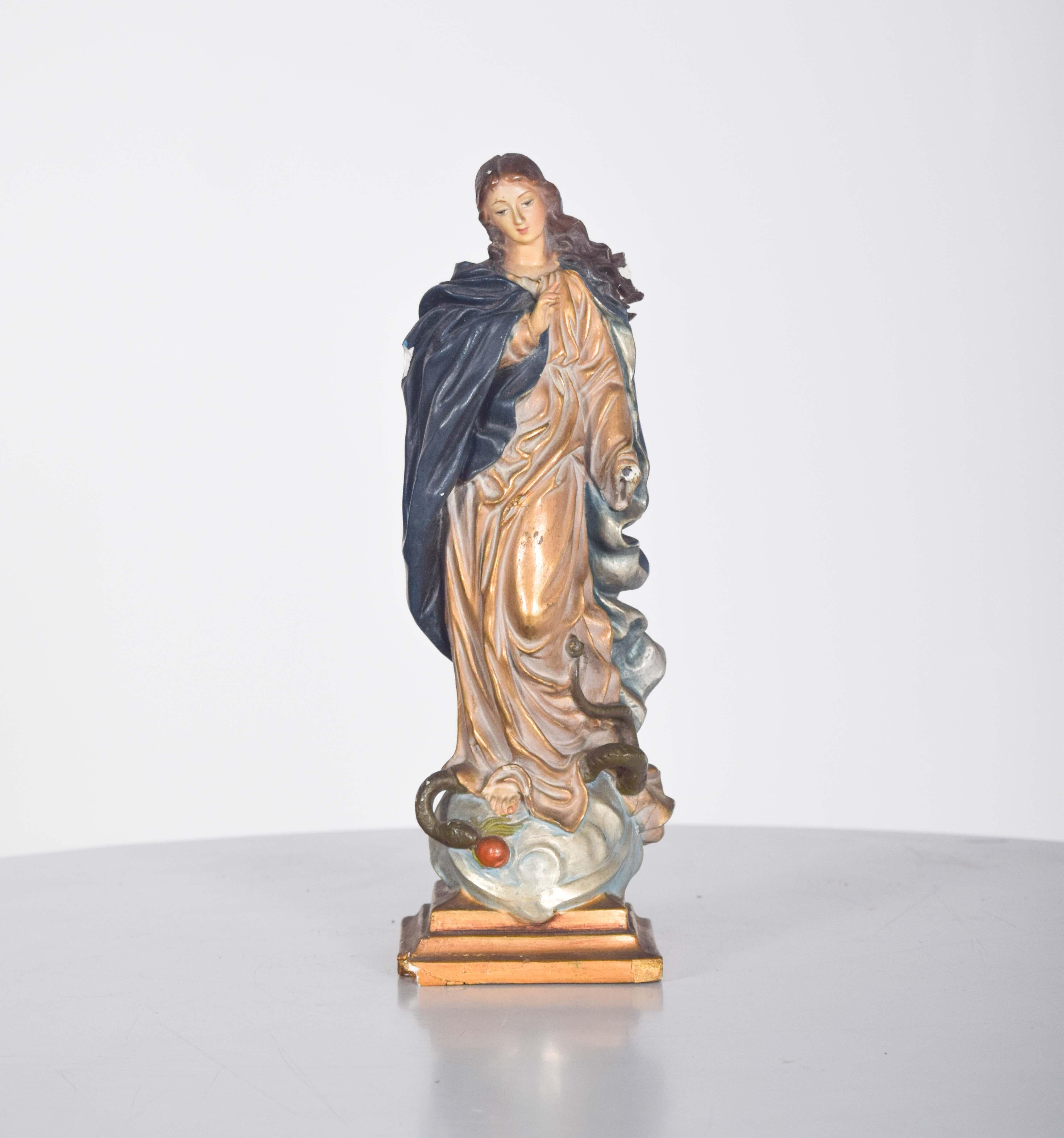 Questa scultura della Signora delle Grazie, realizzata in gesso, emana eleganza e bellezza classica. La figura è avvolta in un fluente mantello blu che ricade delicatamente intorno alle sue forme, aggiungendo un senso di movimento e grazia. Ai suoi