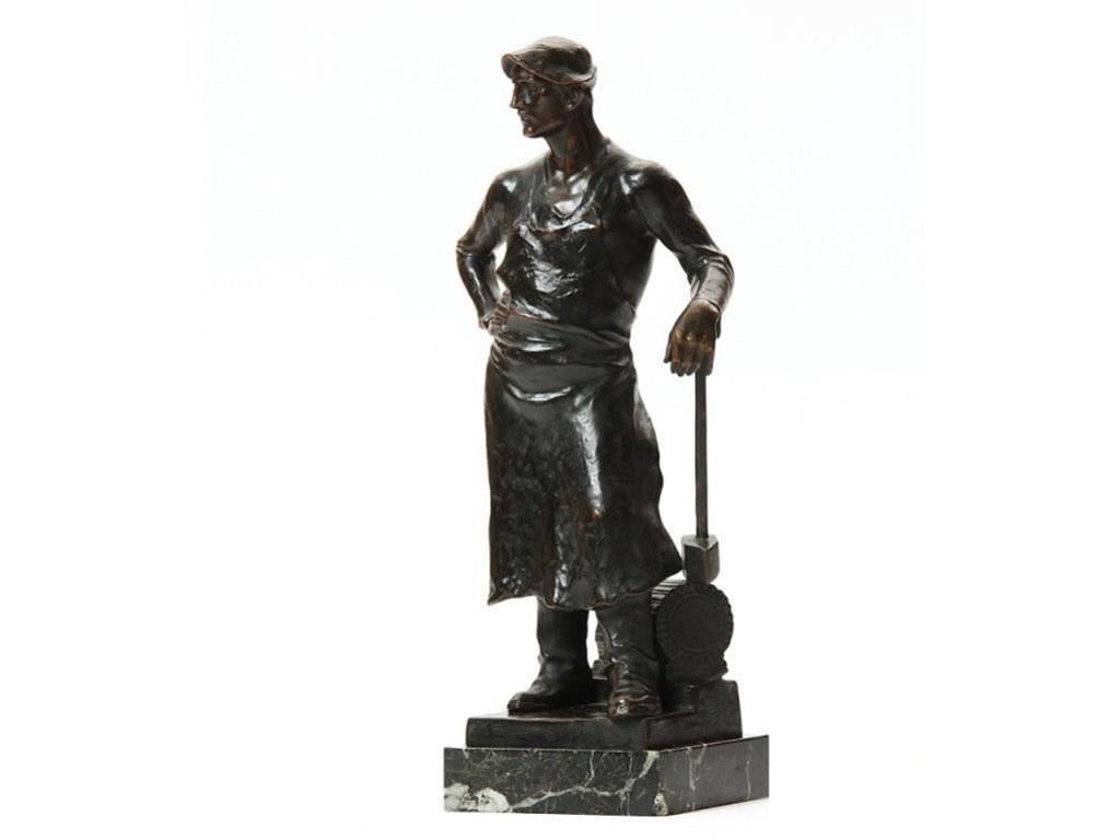 Statue en bronze d'un forgeron sur un socle en marbre.