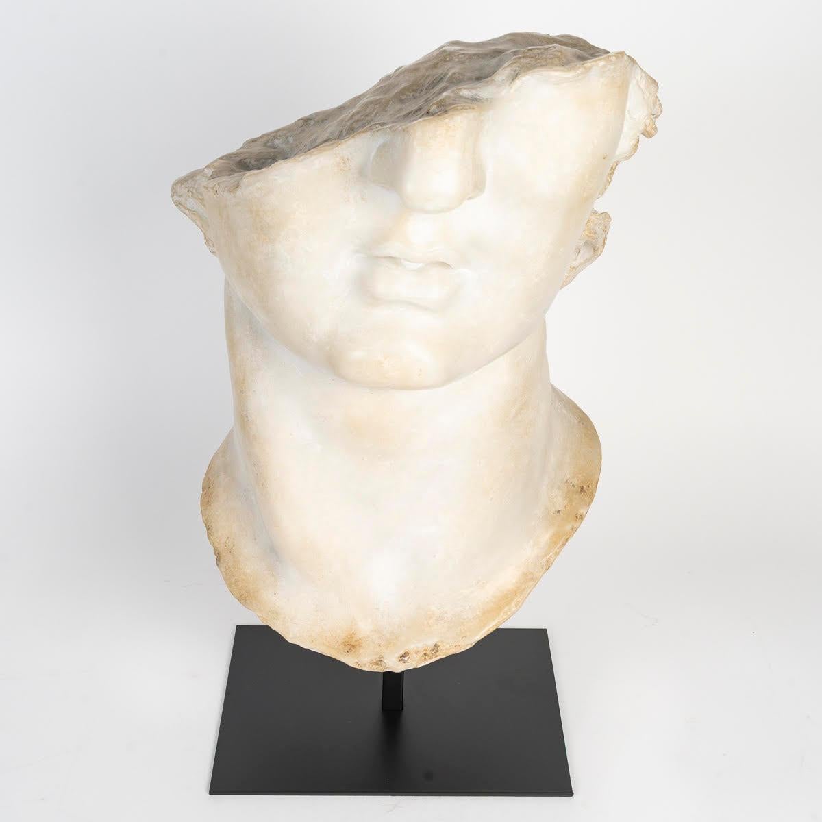 Sculpture representing a fragment of the bust of Apollo.

Sculpture in resin and plaster, metal base, representing a fragment of a bust of Apollo, Greco/Roman style.
H: 63cm, W: 32cm, D: 33cm