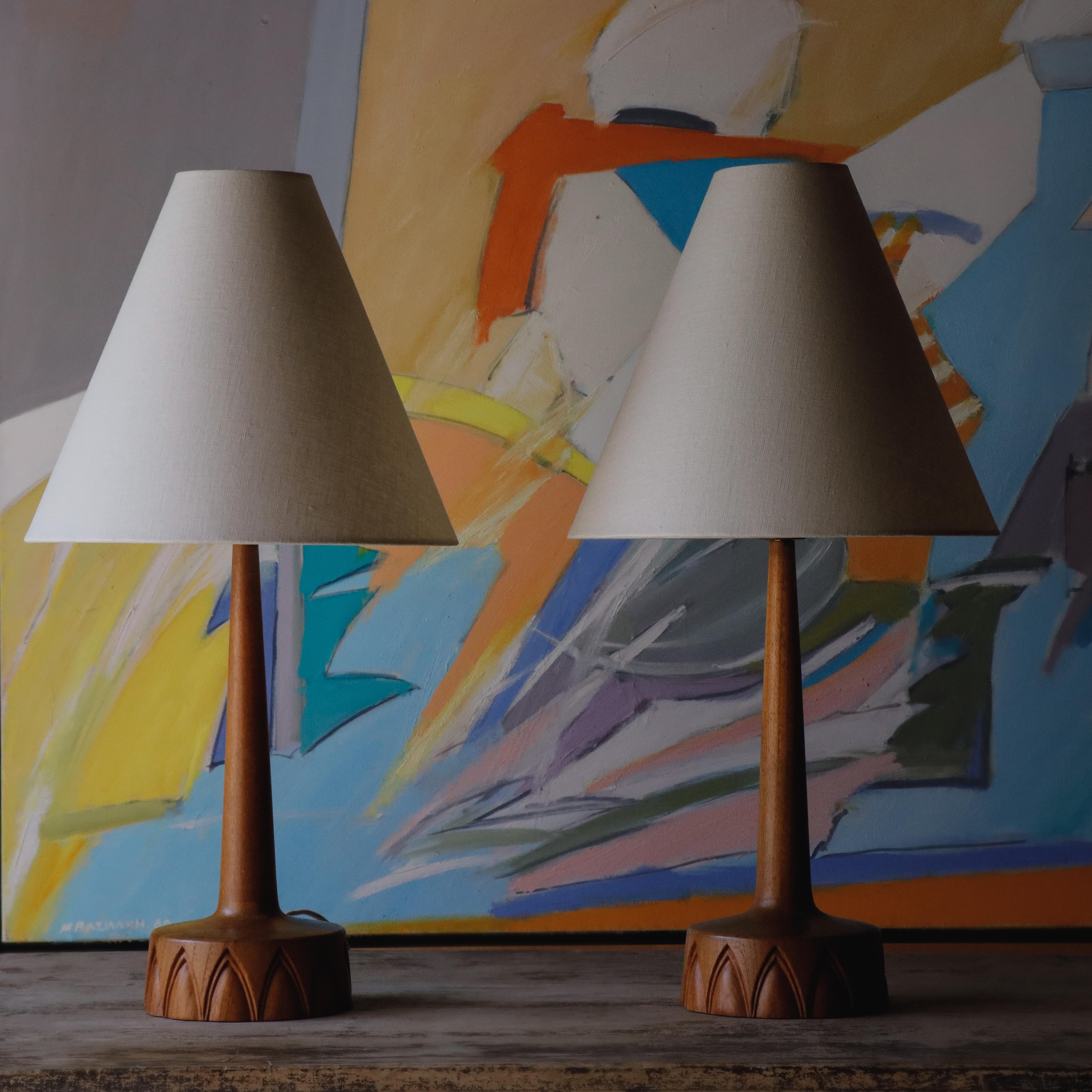 A beautifully understated pair of table lamps by AB Tranås Stilarmatur, a Swedish lighting firm known for clean lines and exceptional craftsmanship.

 Made in solid teak with organic carved bases and newly rewired for US use. We topped them with