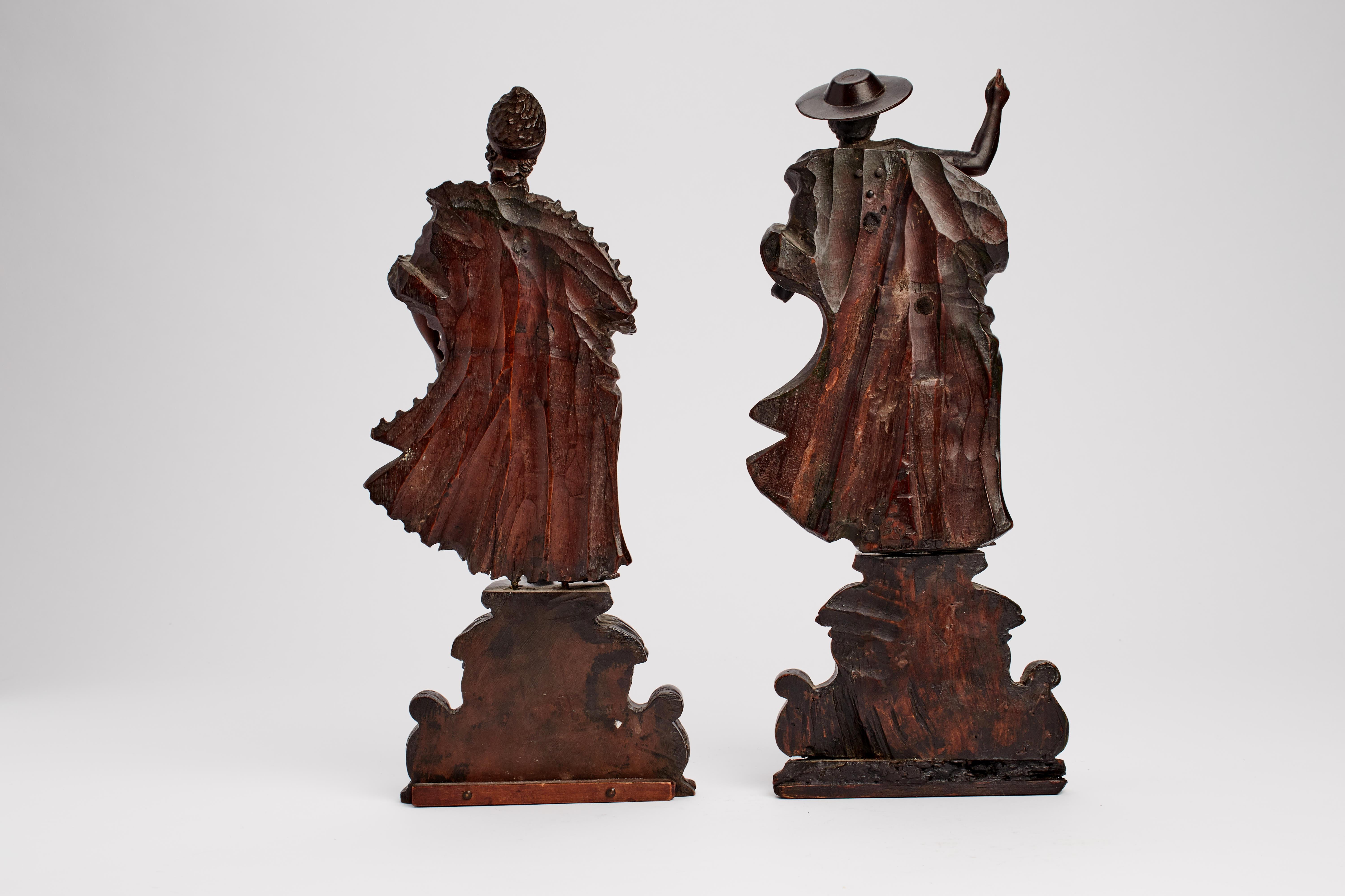 Over a late baroque richly sculpted and engraved base with a cartouche over the front, the moved figures partially covered with wide fur and drape, depicting a bishop and a cardinal. Swiss pine wood. Venice 1730 ca.