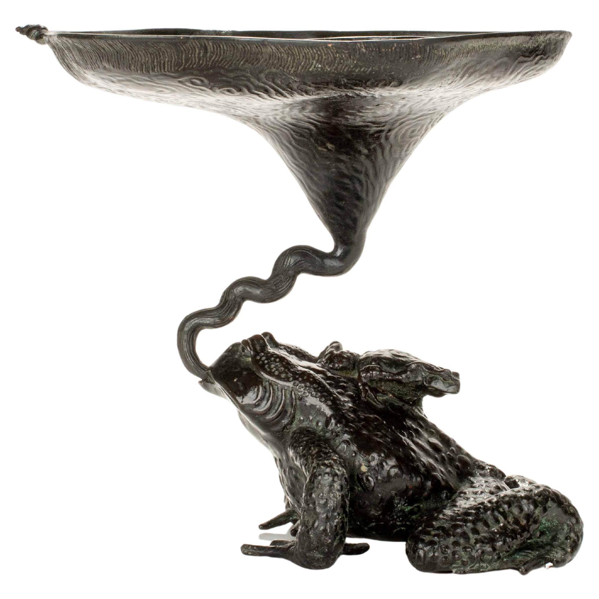 Bronze sculpture depicting two toads with an ikebana vase