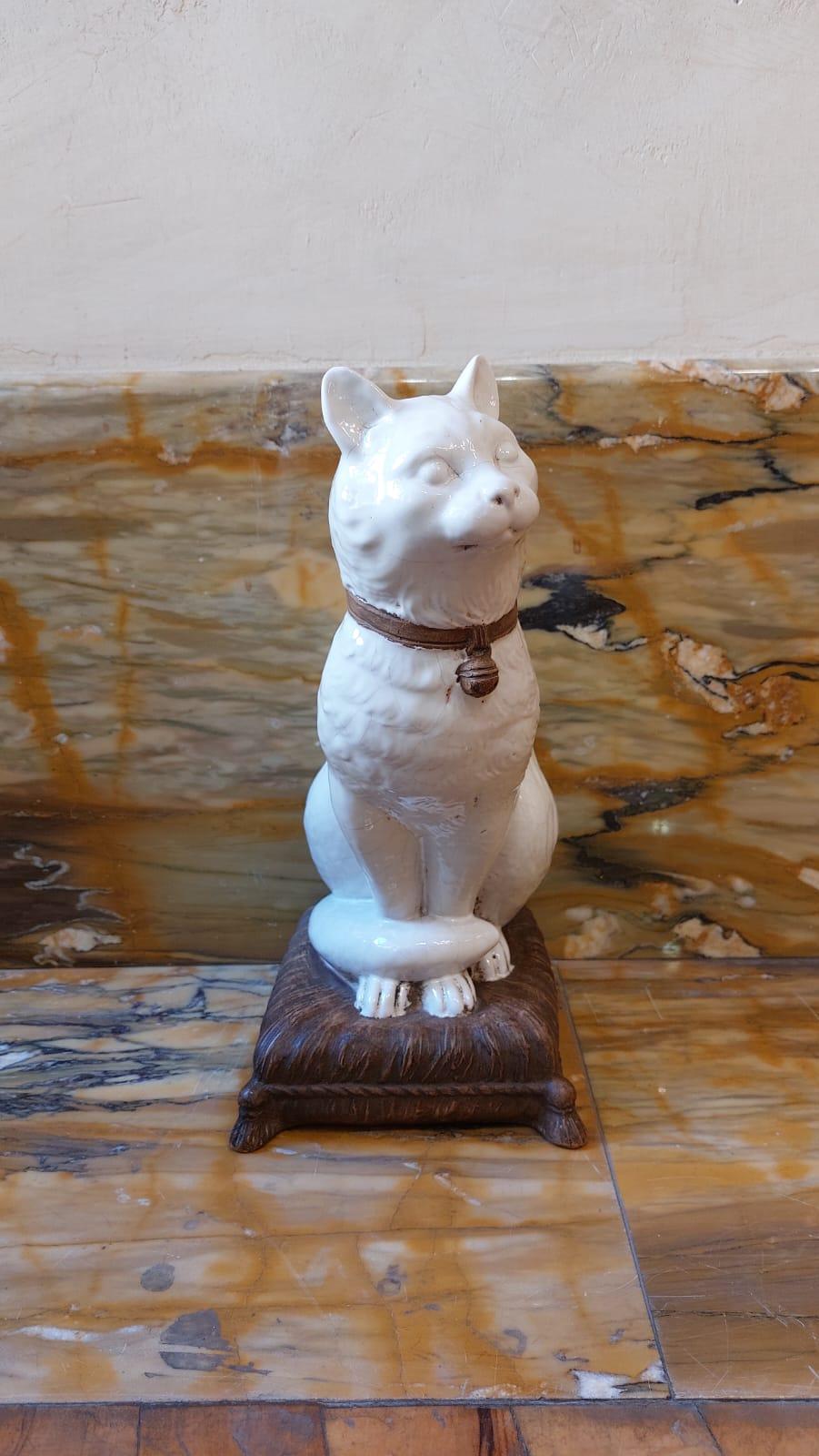La scultura, raffigurante un gatto, è in ceramica dipinta di bianco e smaltata, fatta eccezione per il collare dell'animale con il campanellino (color marrone chiaro) e il cuscino, che è la base su cui appoggia il gatto (color marrone