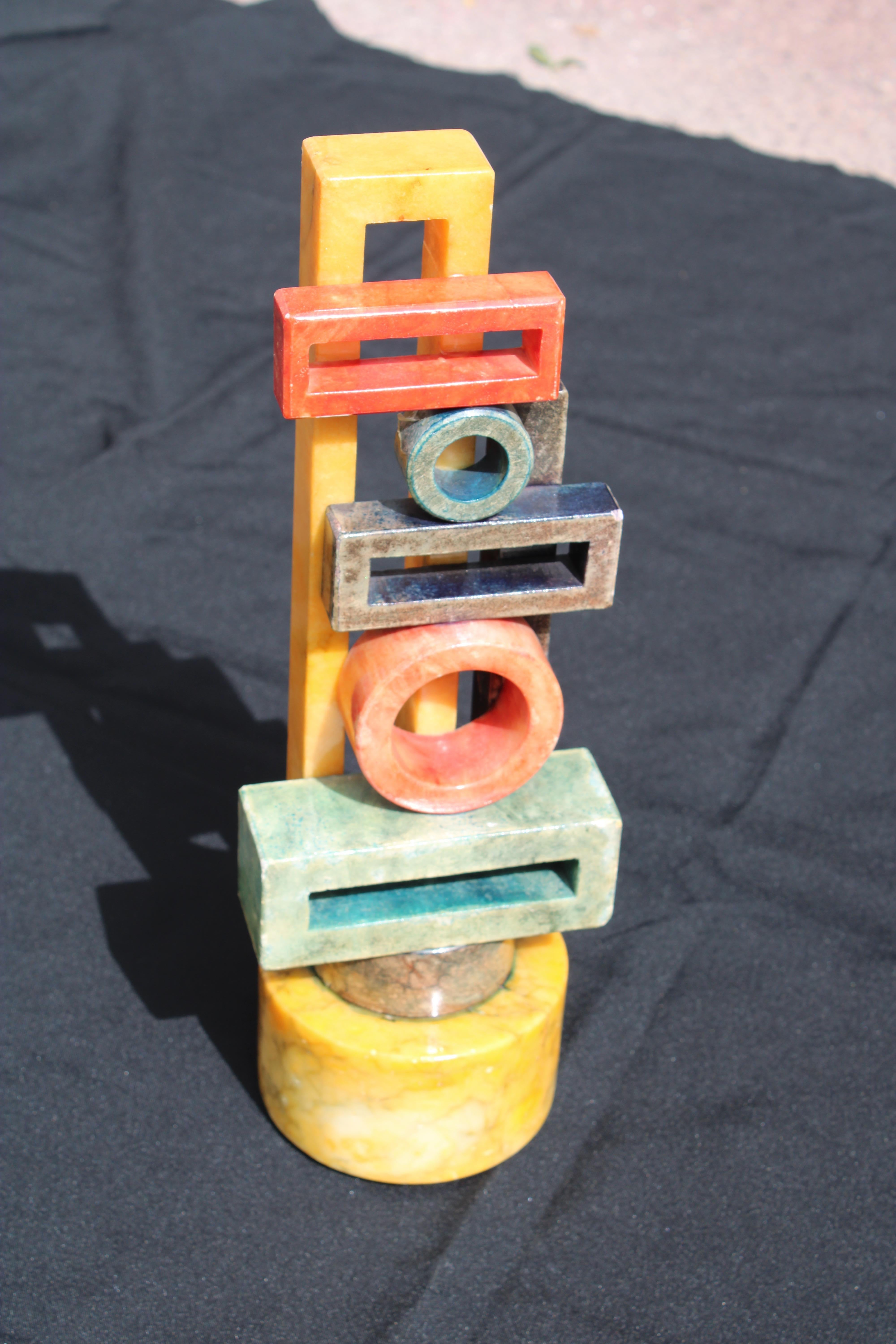 Scultura divertente in marmo dipinto con figure geometriche colorate.